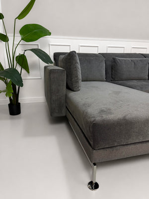 Ausstellungsstück Brühl Moule Designer Stoff Sofa in Grau vor einer Wand, stilvoll und modern eingerichtet.