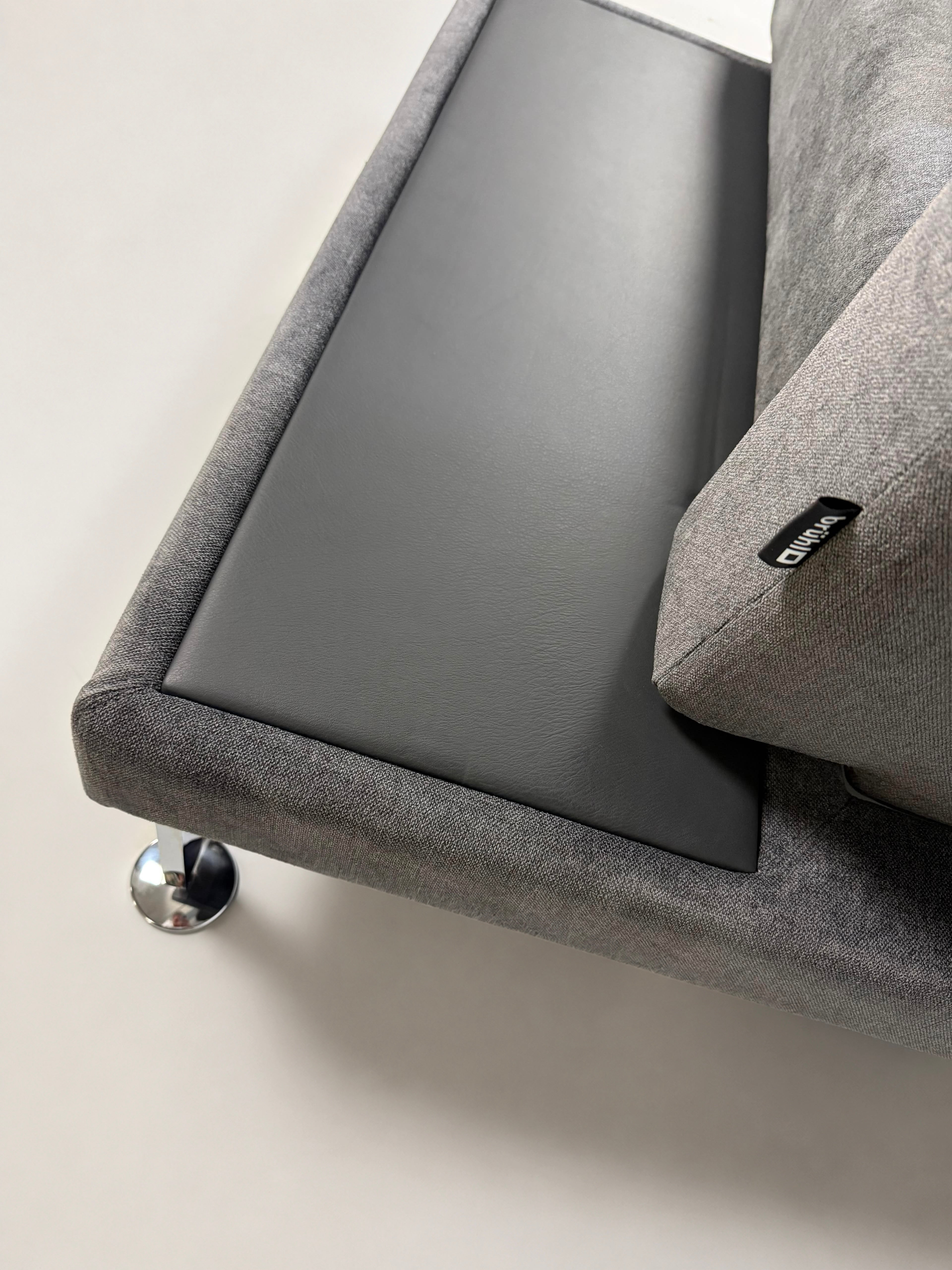Ausstellungsstück Brühl Moule Designer Stoff Sofa in Grau vor einer Wand, stilvoll und modern eingerichtet.