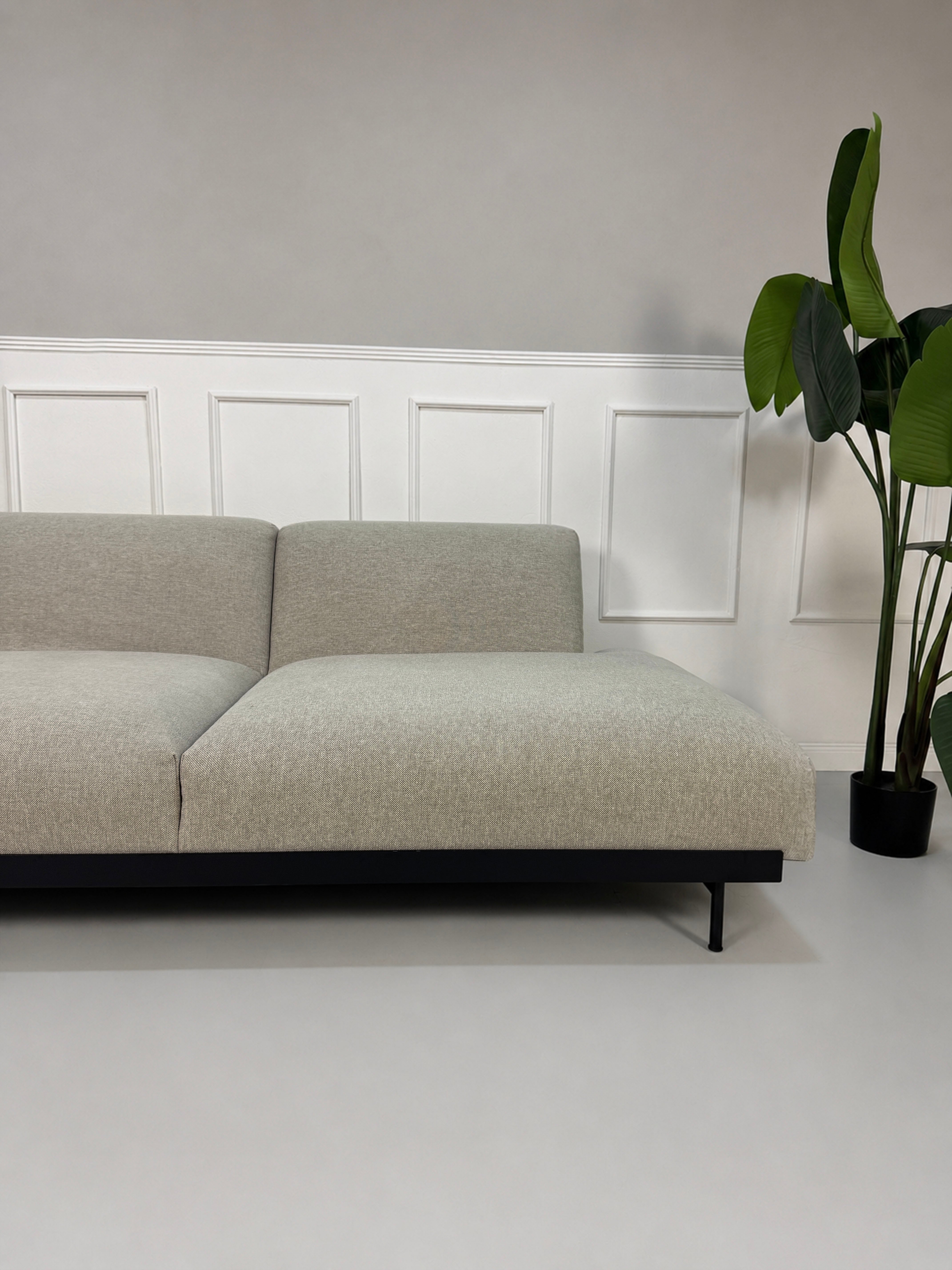 Gebrauchtes graues Muuto Situ Designer Stoff Sofa vor einer Wand, stilvoll und modern eingerichtet.