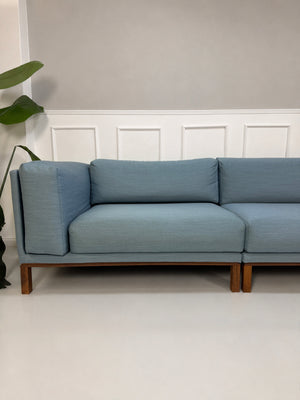 Gebrauchtes blaues Bolia Cosy Designer Stoff Sofa vor einer Wand, stilvoll und modern eingerichtet.