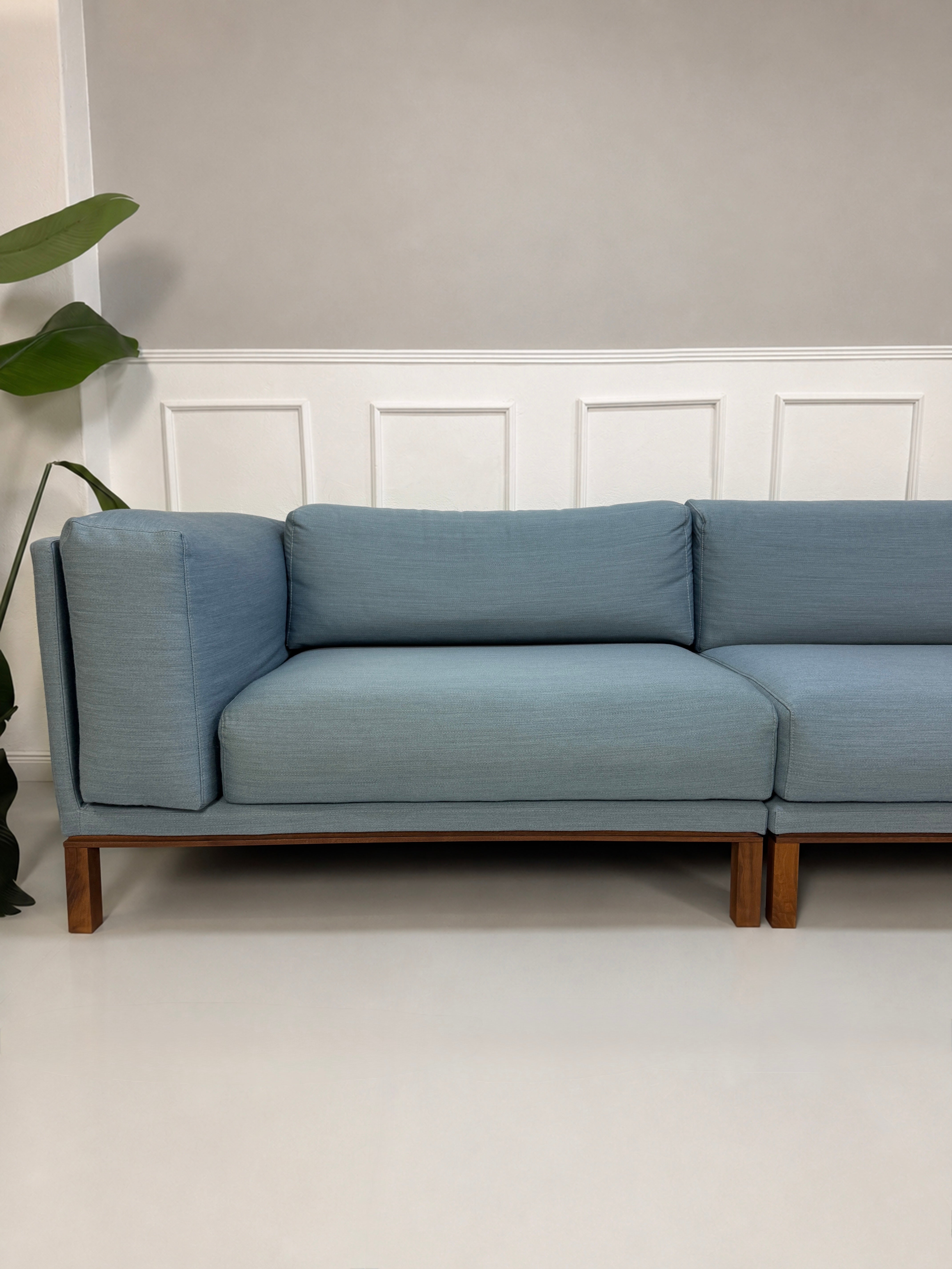 Gebrauchtes blaues Bolia Cosy Designer Stoff Sofa vor einer Wand, stilvoll und modern eingerichtet.