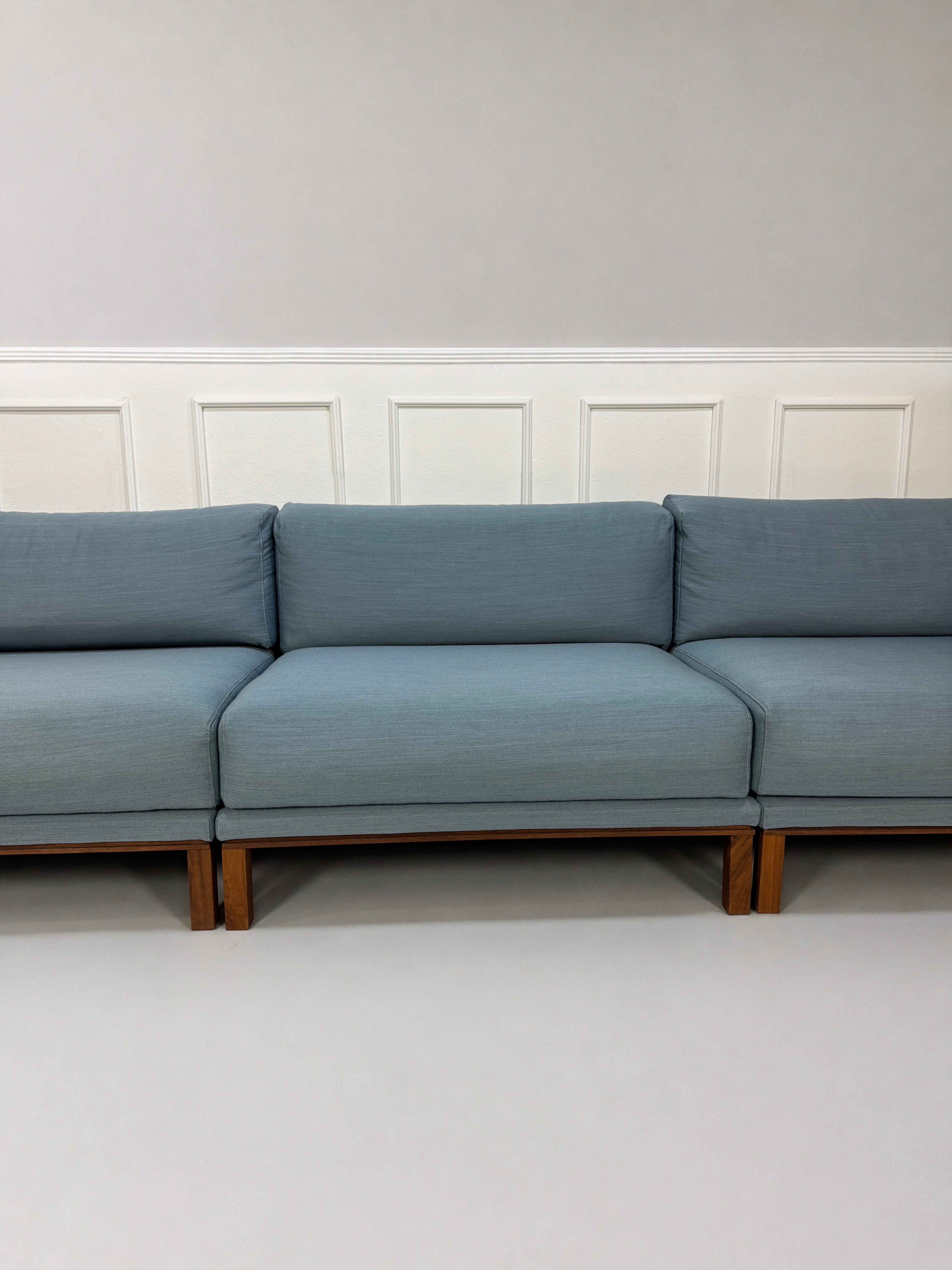 Gebrauchtes blaues Bolia Cosy Designer Stoff Sofa vor einer Wand, stilvoll und modern eingerichtet.