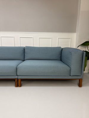 Gebrauchtes blaues Bolia Cosy Designer Stoff Sofa vor einer Wand, stilvoll und modern eingerichtet.
