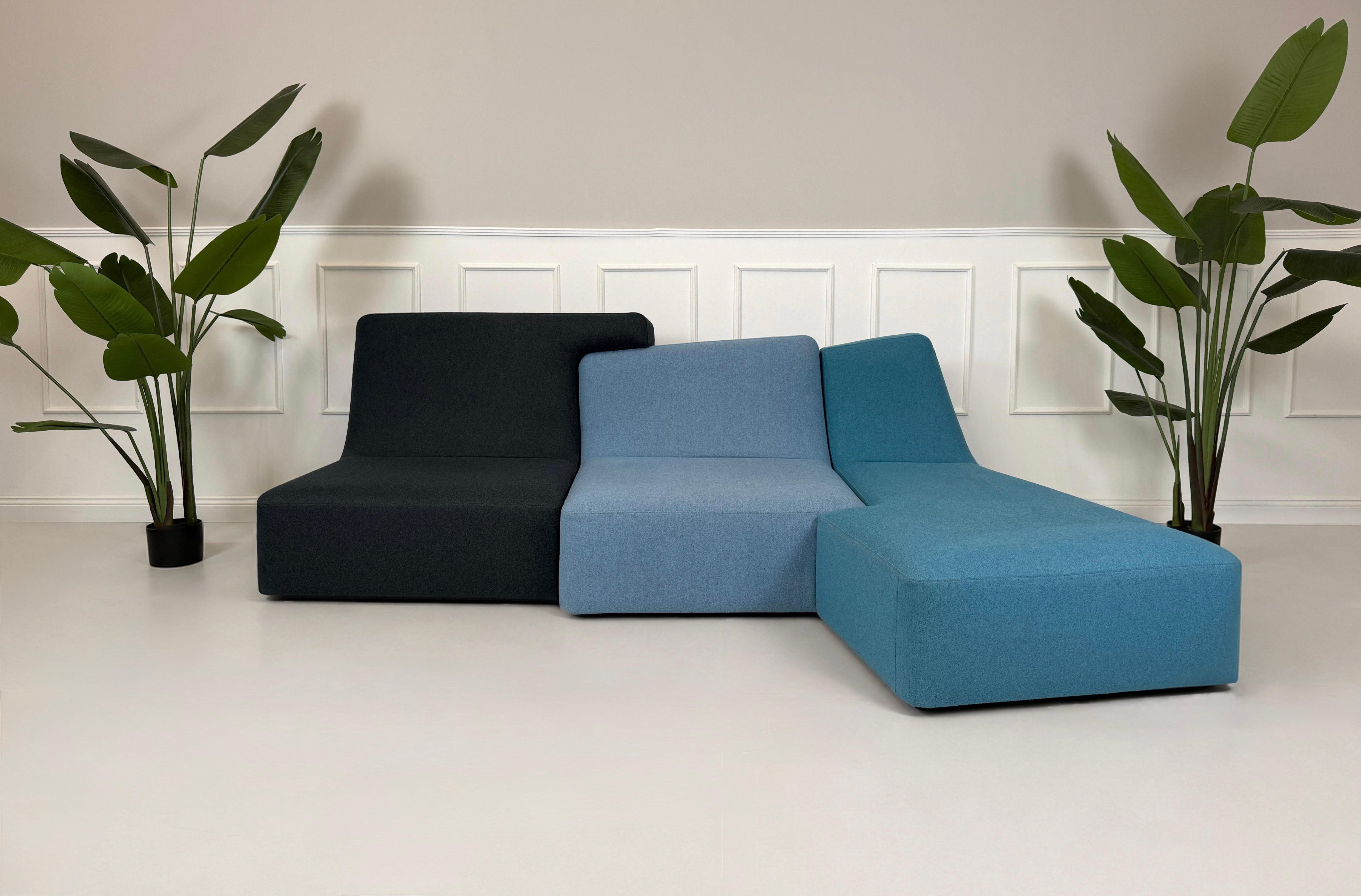 Gebrauchtes blaues Ligne Roset Confluences Designer Stoff Sofa vor einer Wand, stilvoll und modern eingerichtet.