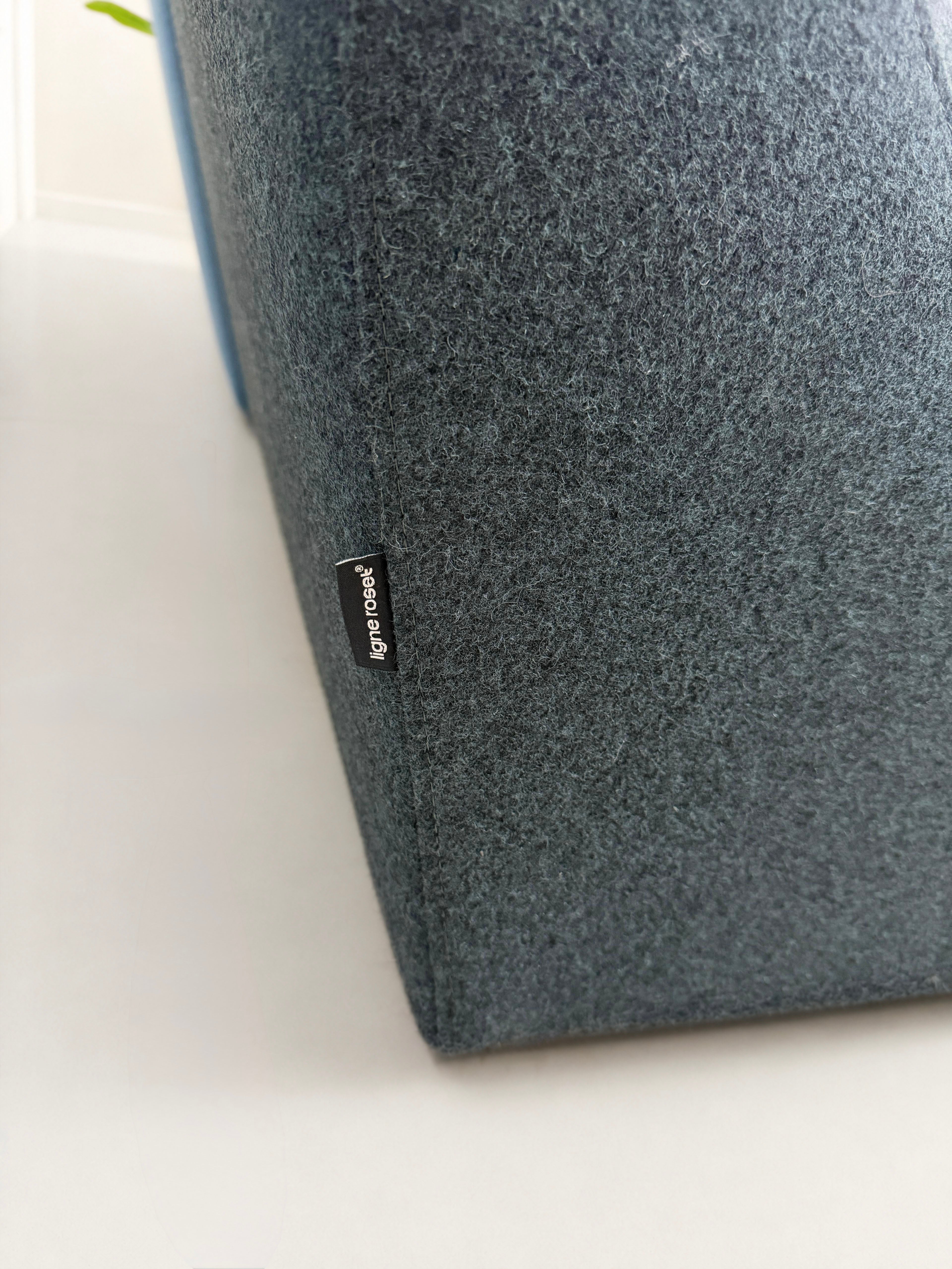 Gebrauchtes blaues Ligne Roset Confluences Designer Stoff Sofa vor einer Wand, stilvoll und modern eingerichtet.