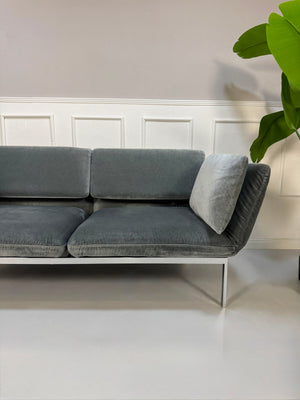 Gebrauchtes graues Brühl Roro medium Designer Stoff Sofa vor einer Wand, stilvoll und modern eingerichtet.