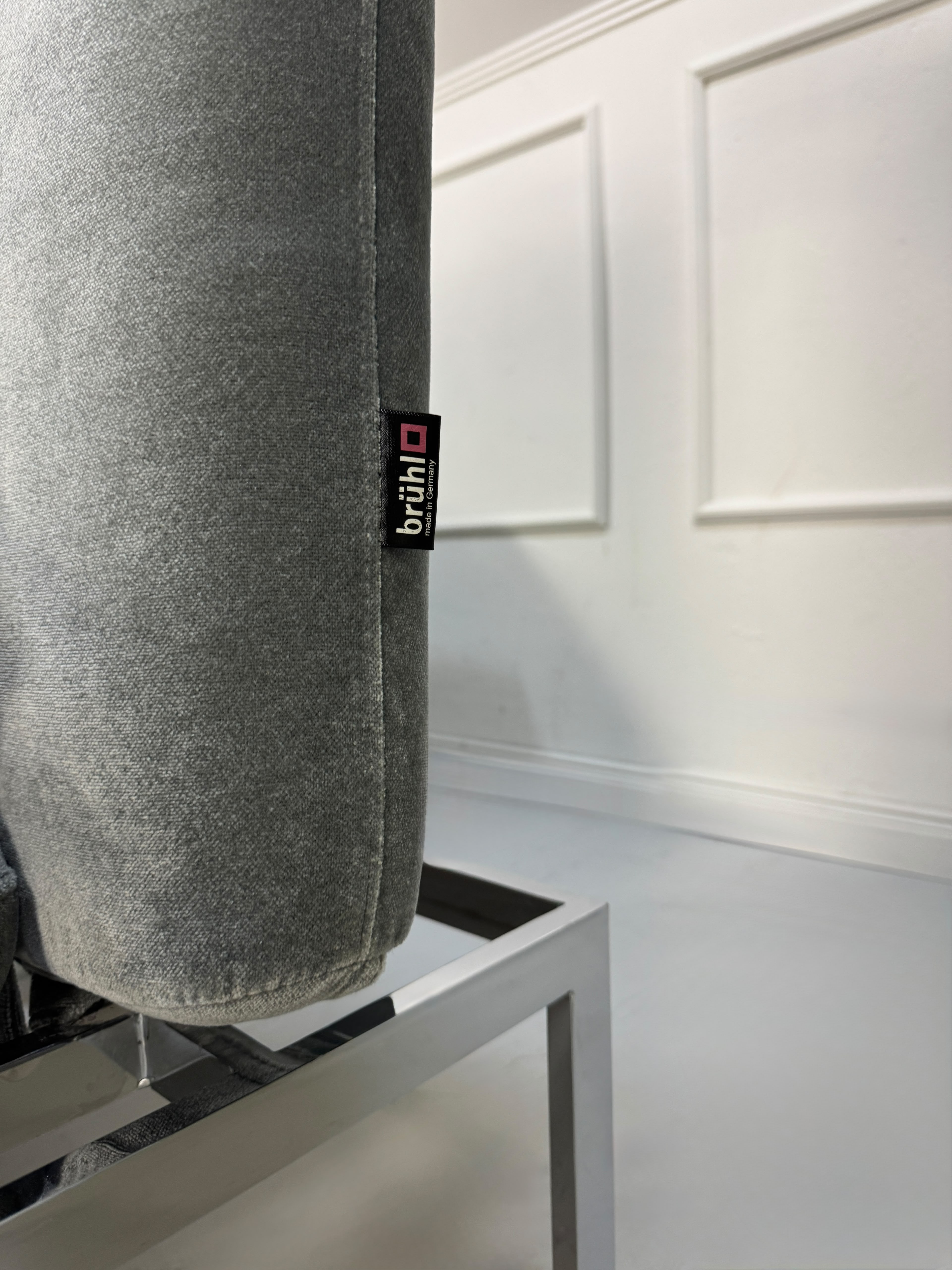 Gebrauchtes graues Brühl Roro medium Designer Stoff Sofa vor einer Wand, stilvoll und modern eingerichtet.