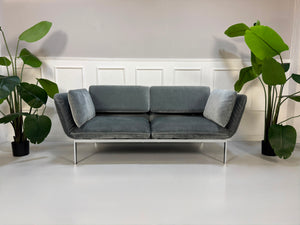 Gebrauchtes graues Brühl Roro medium Designer Stoff Sofa vor einer Wand, stilvoll und modern eingerichtet.
