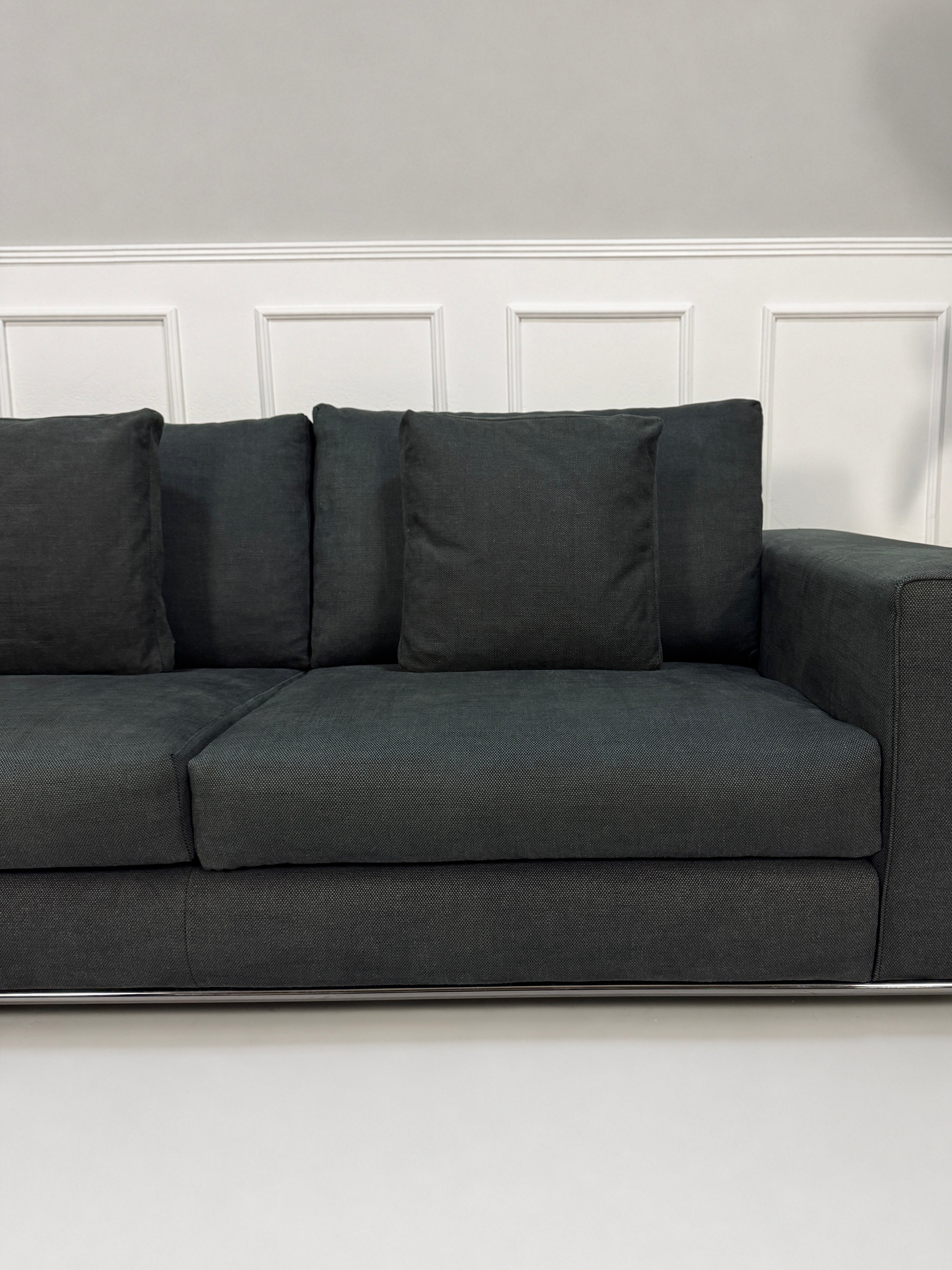 Gebrauchtes graues Minotti Hamilton Designer Stoff Sofa vor einer Wand, stilvoll und modern eingerichtet.