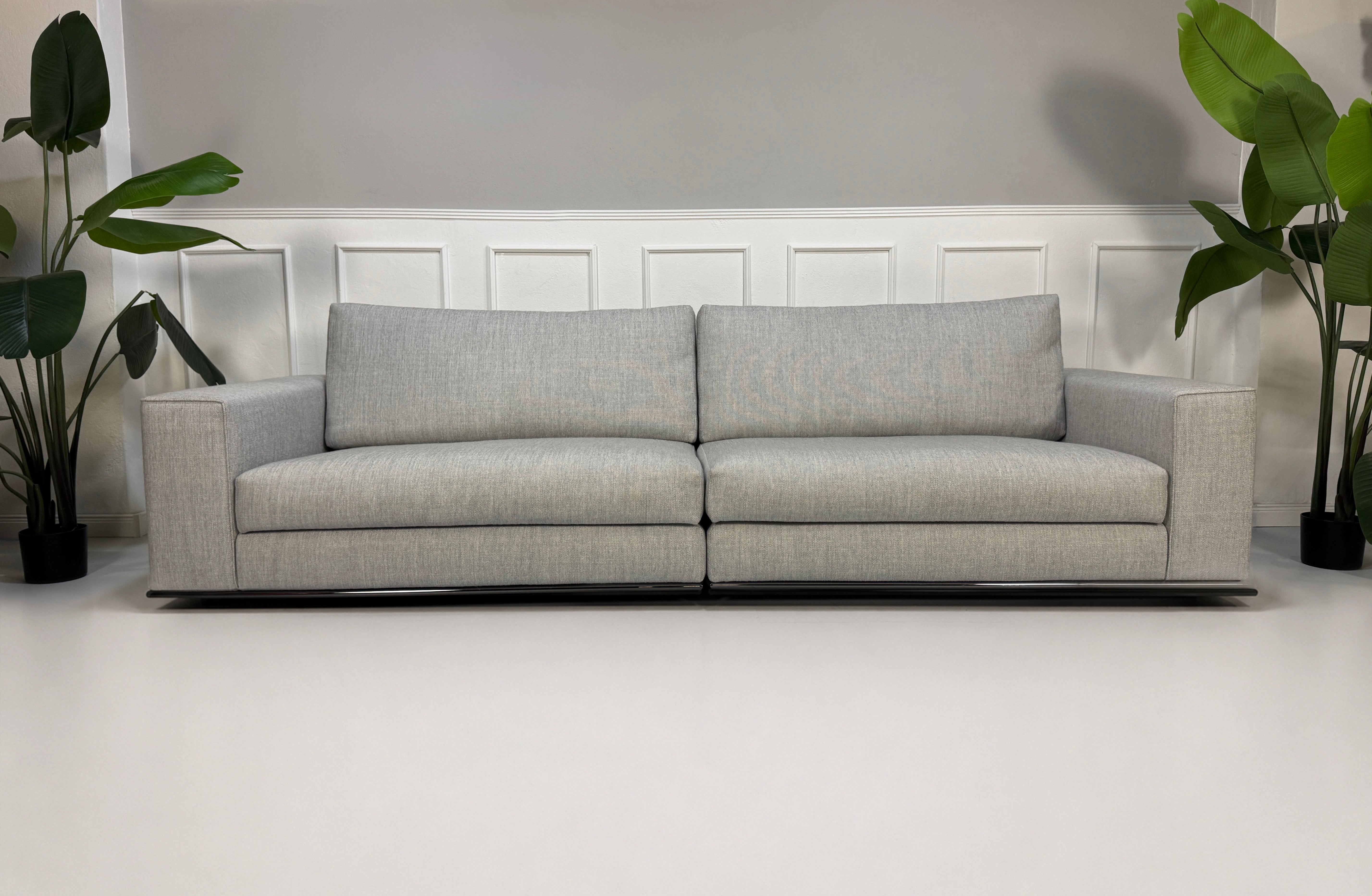 Ausstellungsstück graues Minotti Hamilton Designer Stoff Sofa vor einer Wand, stilvoll und modern eingerichtet.