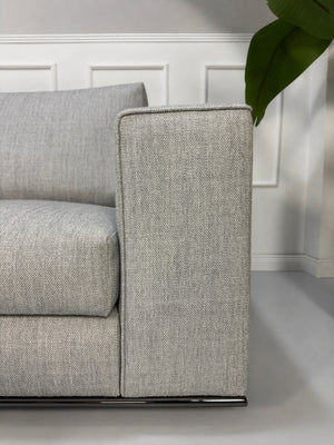 Ausstellungsstück graues Minotti Hamilton Designer Stoff Sofa vor einer Wand, stilvoll und modern eingerichtet.