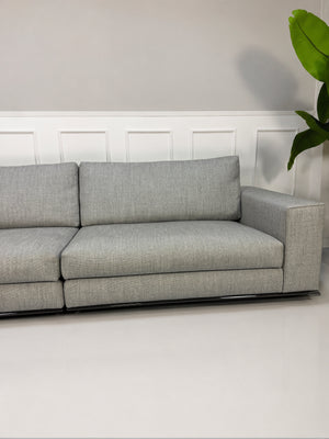 Ausstellungsstück graues Minotti Hamilton Designer Stoff Sofa vor einer Wand, stilvoll und modern eingerichtet.
