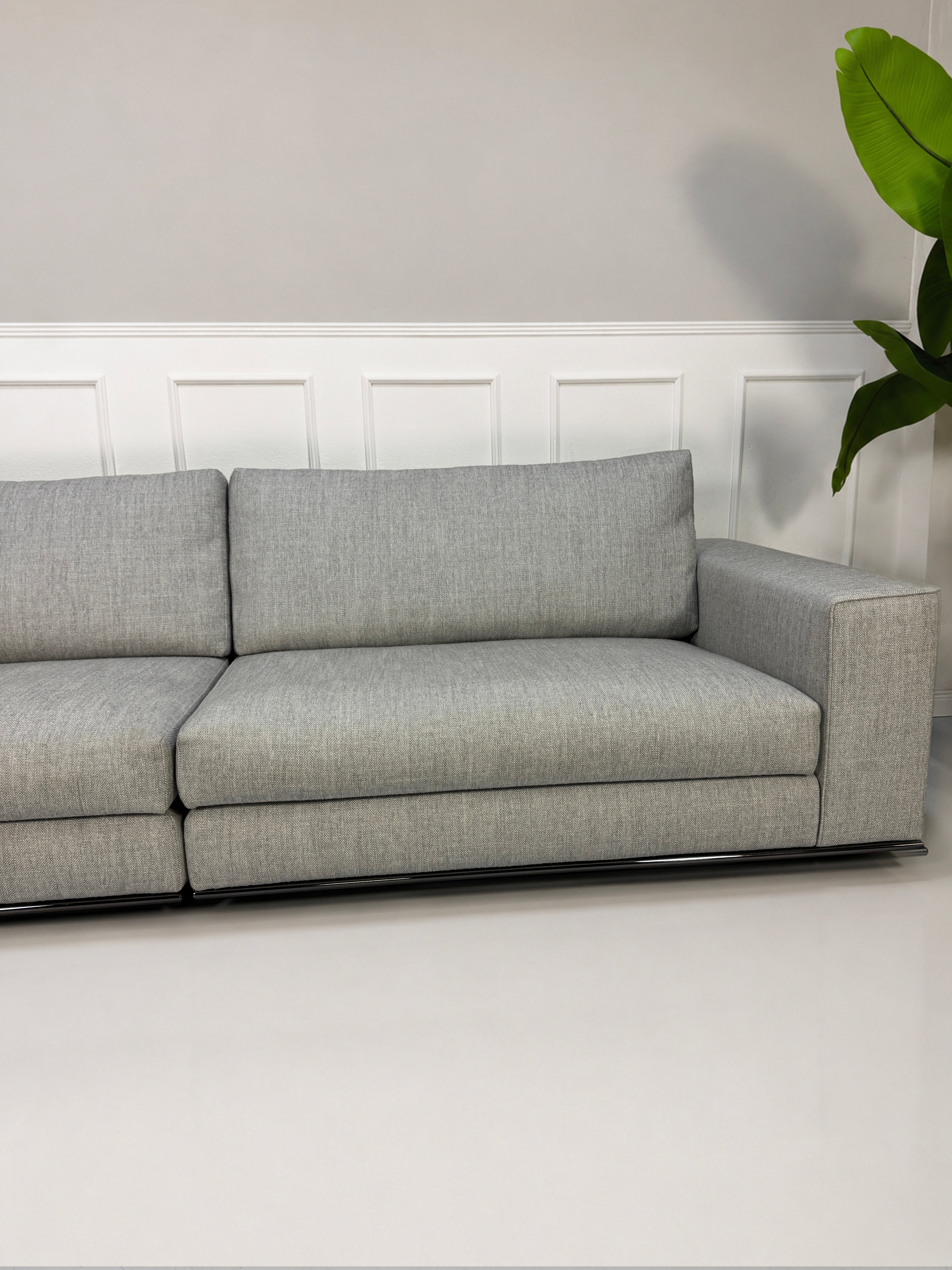 Ausstellungsstück graues Minotti Hamilton Designer Stoff Sofa vor einer Wand, stilvoll und modern eingerichtet.