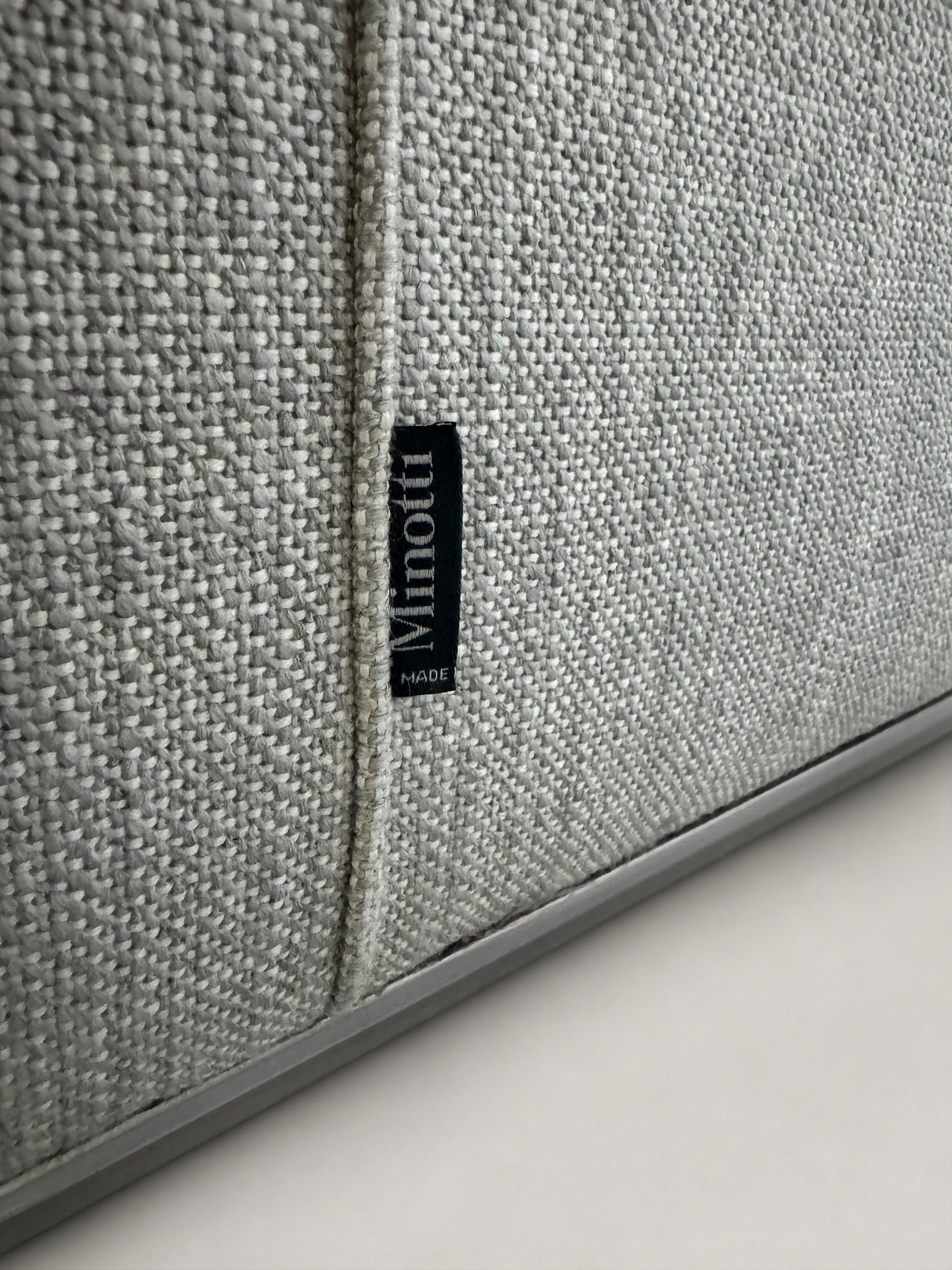 Ausstellungsstück graues Minotti Hamilton Designer Stoff Sofa vor einer Wand, stilvoll und modern eingerichtet.