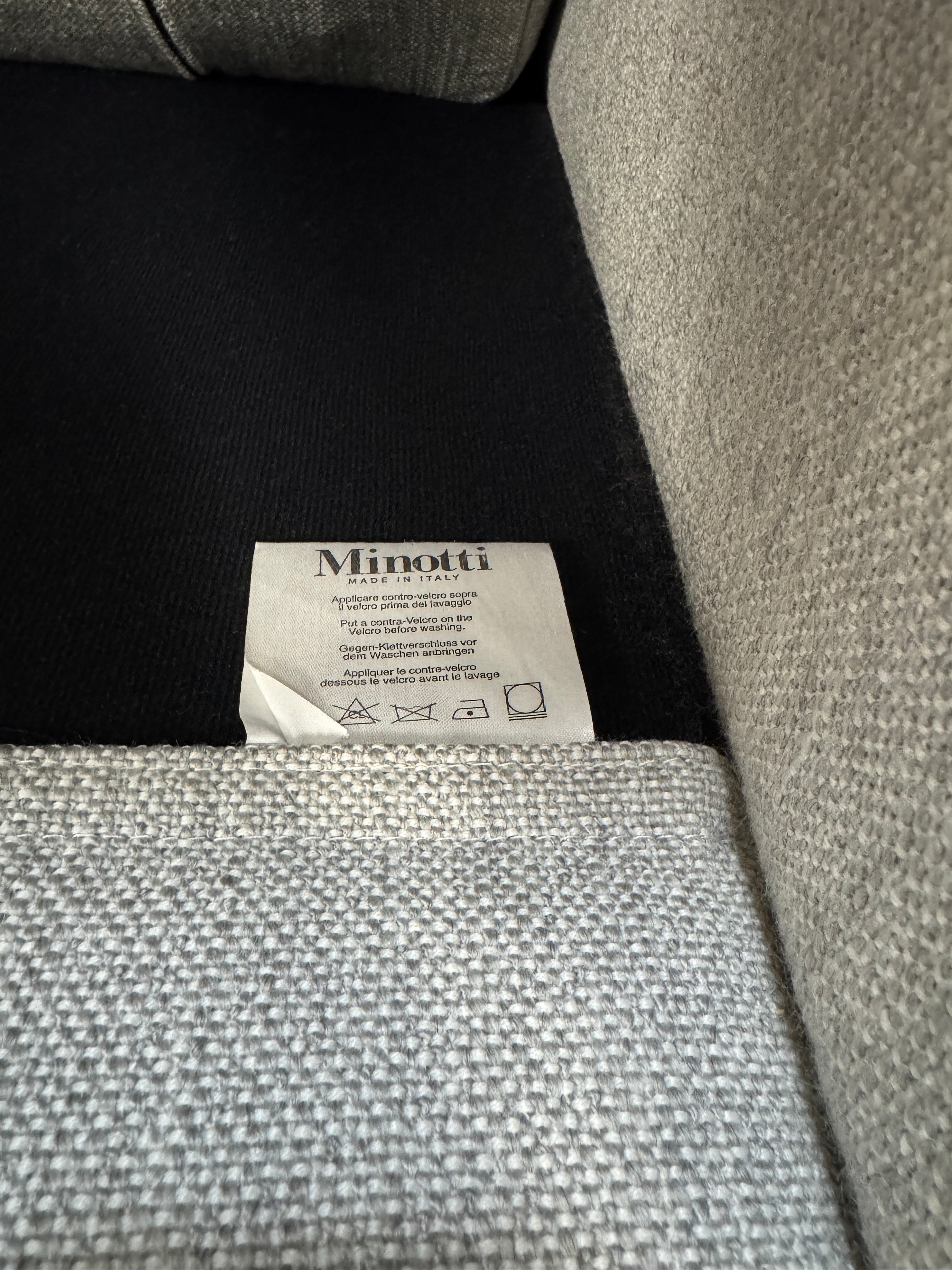 Ausstellungsstück graues Minotti Hamilton Designer Stoff Sofa vor einer Wand, stilvoll und modern eingerichtet.