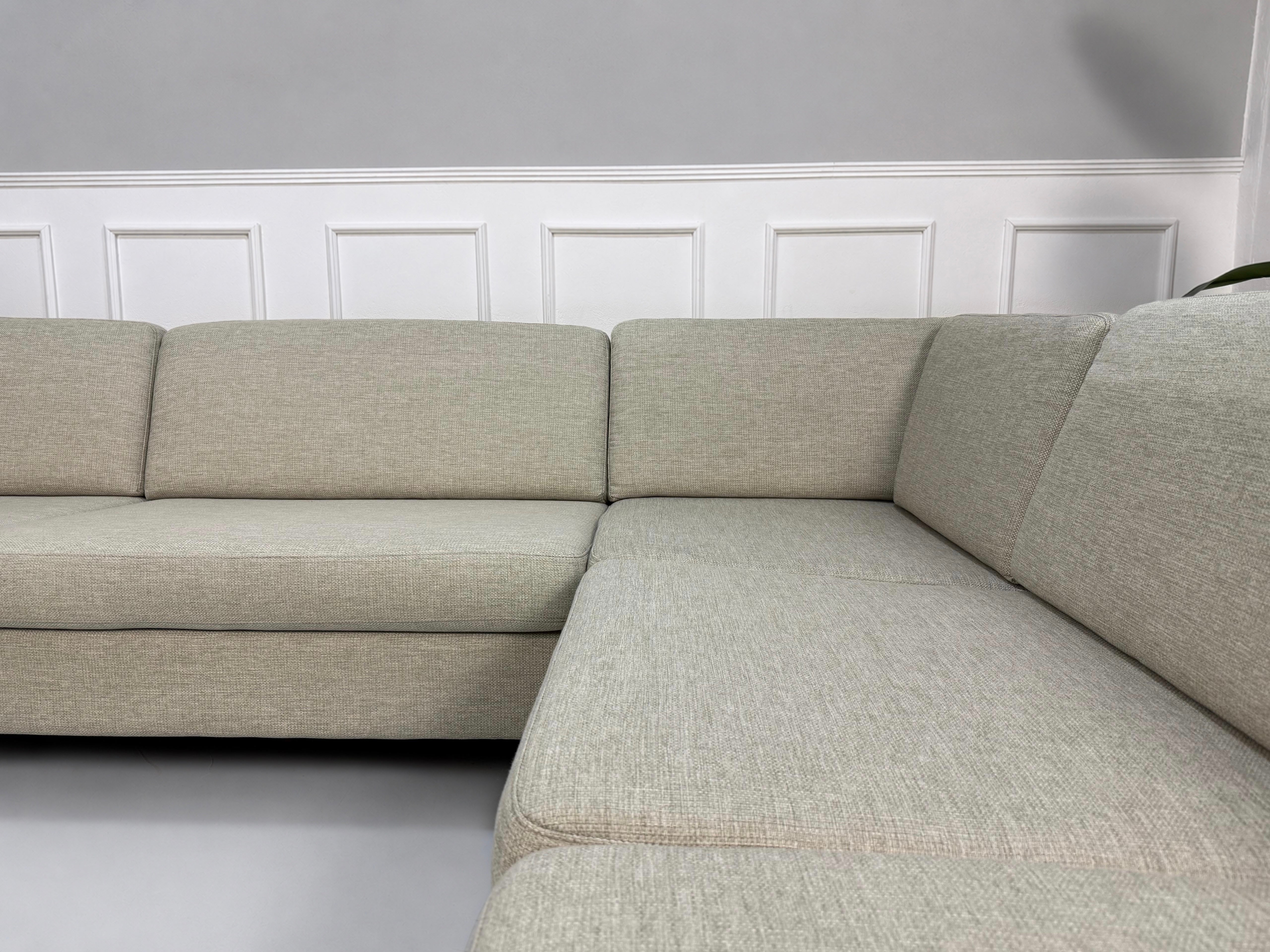 Gebrauchtes beiges Bolia Scandinavia 6 Sitzer Designer Stoff Sofa vor einer Wand, stilvoll und modern eingerichtet.