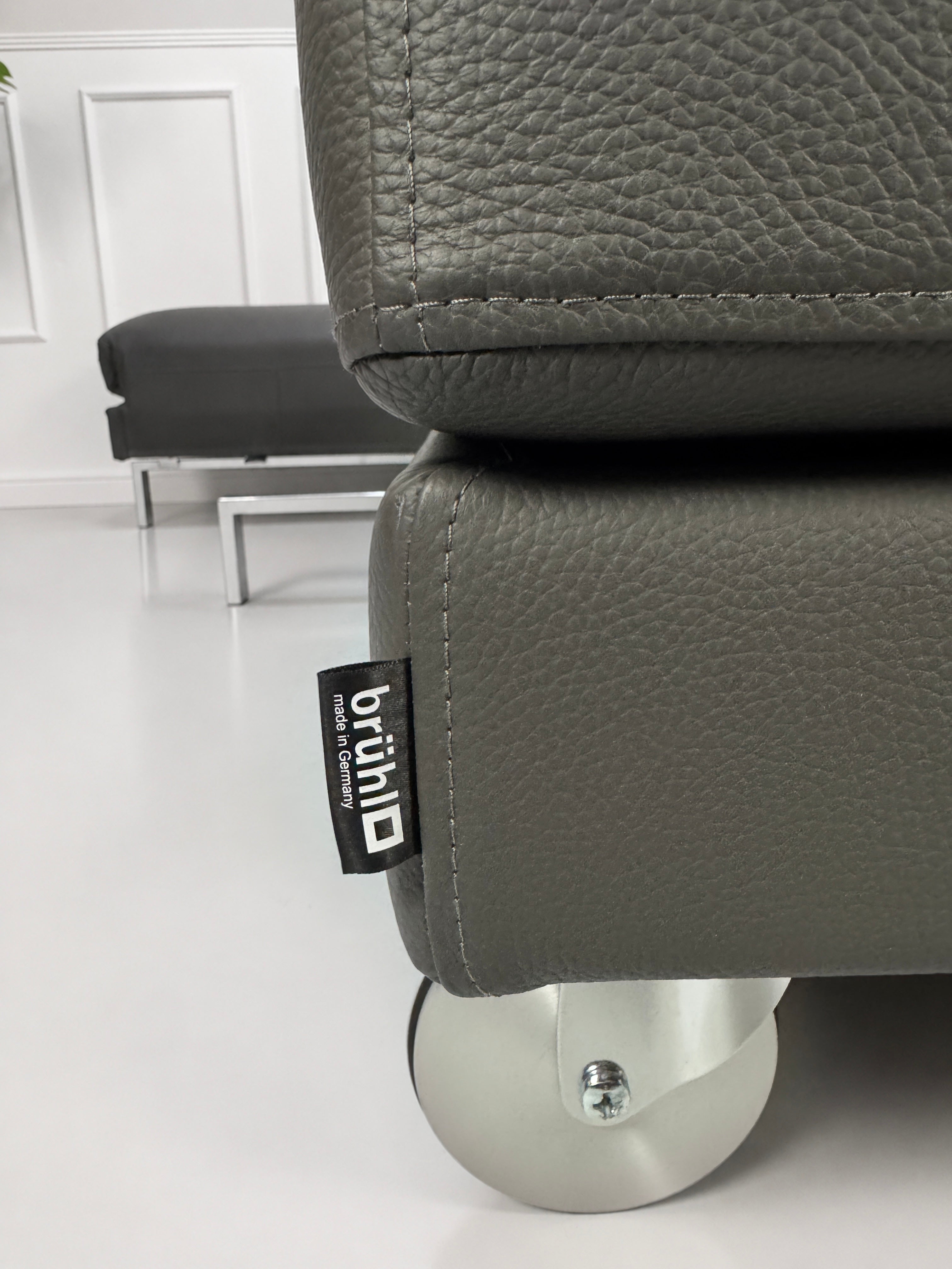 Ausstellungsstück Brühl Four Two  Designer Leder Sofa vor einer Wand, stilvoll und modern eingerichtet.