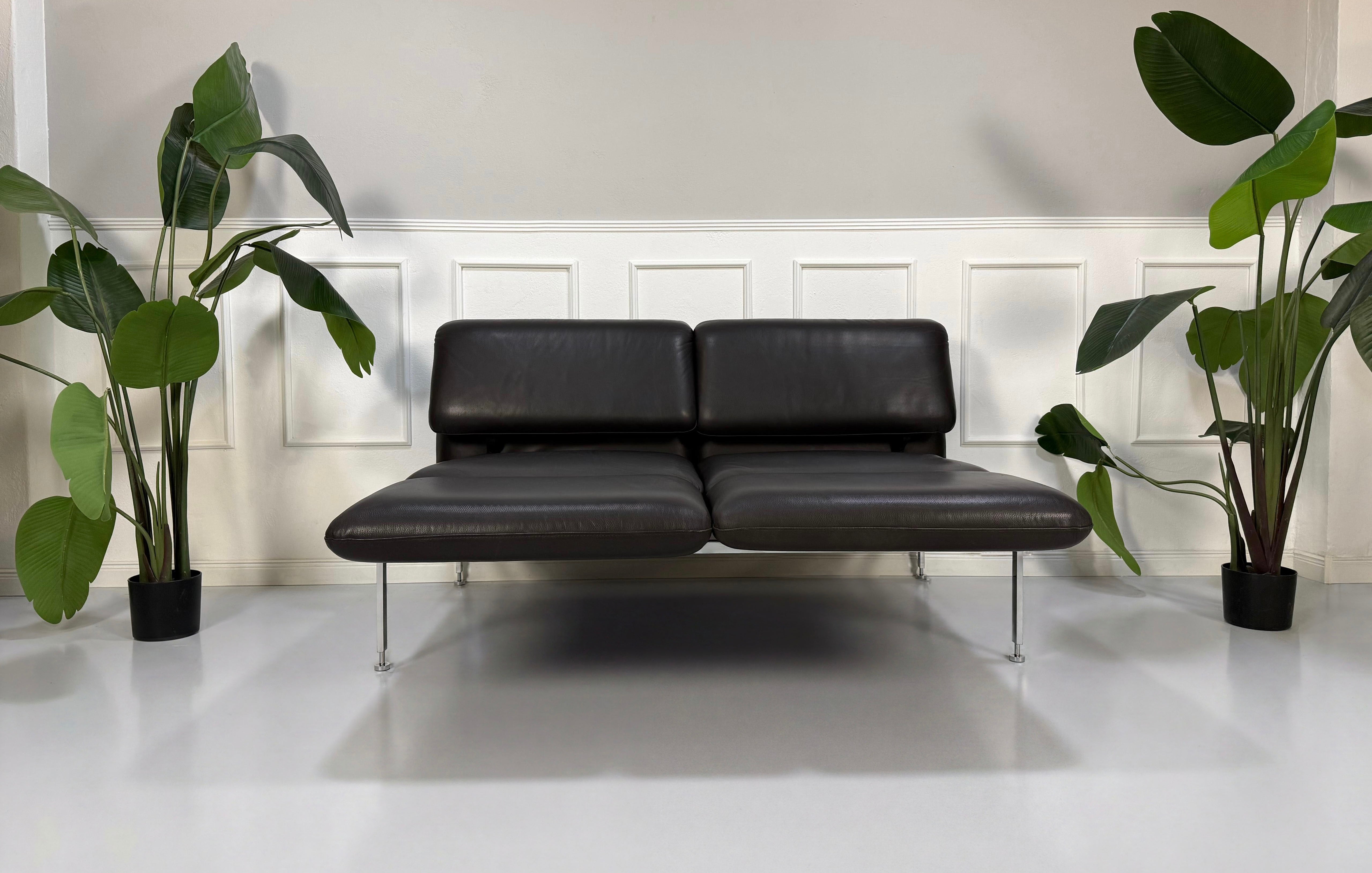 Gebrauchtes schwarzes Brühl Roro Designer Leder Sofa vor einer Wand, stilvoll und modern eingerichtet.