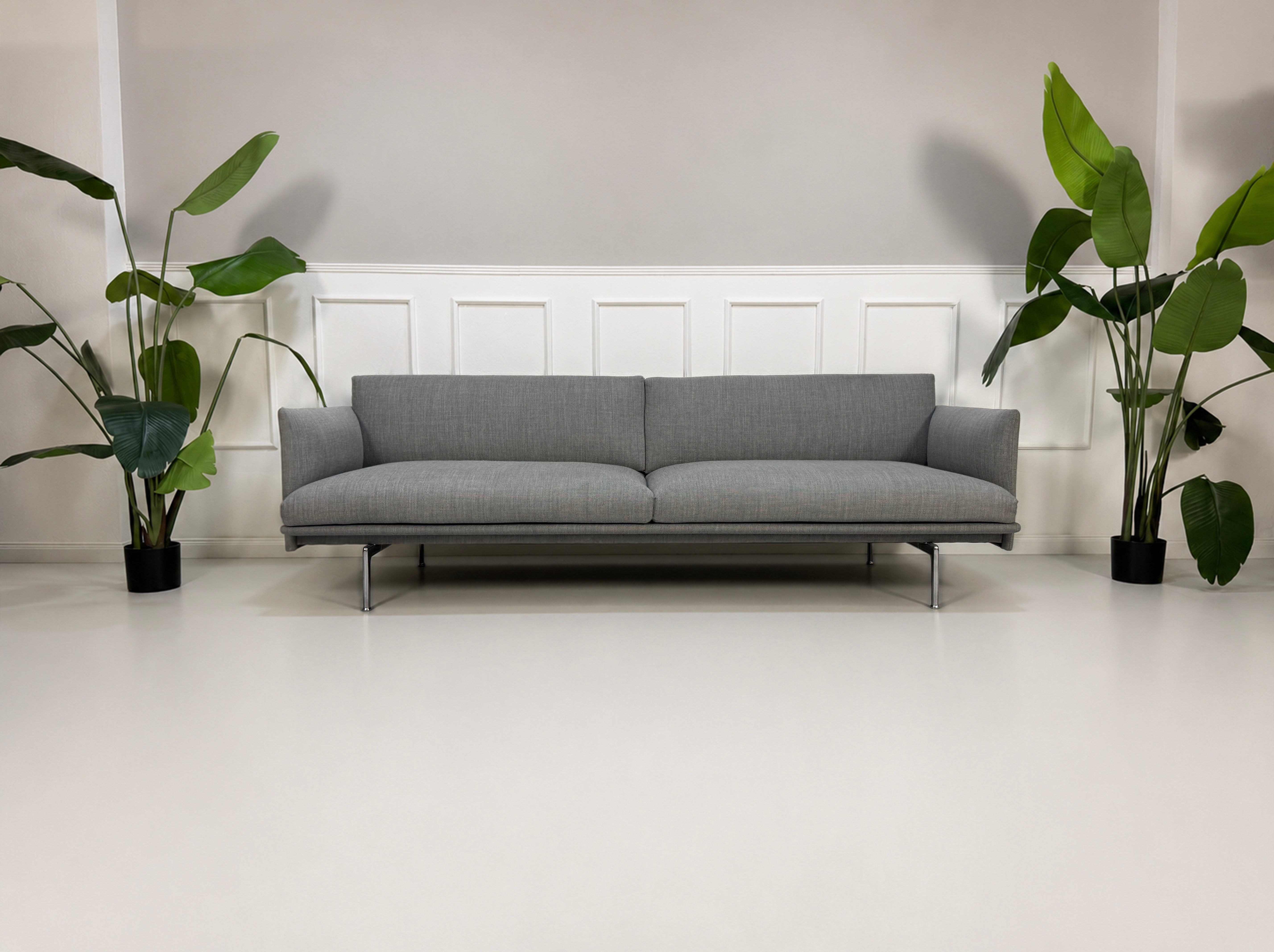 Gebrauchtes graues Muuto Outline Designer Stoff Sofa vor einer Wand, stilvoll und modern eingerichtet.