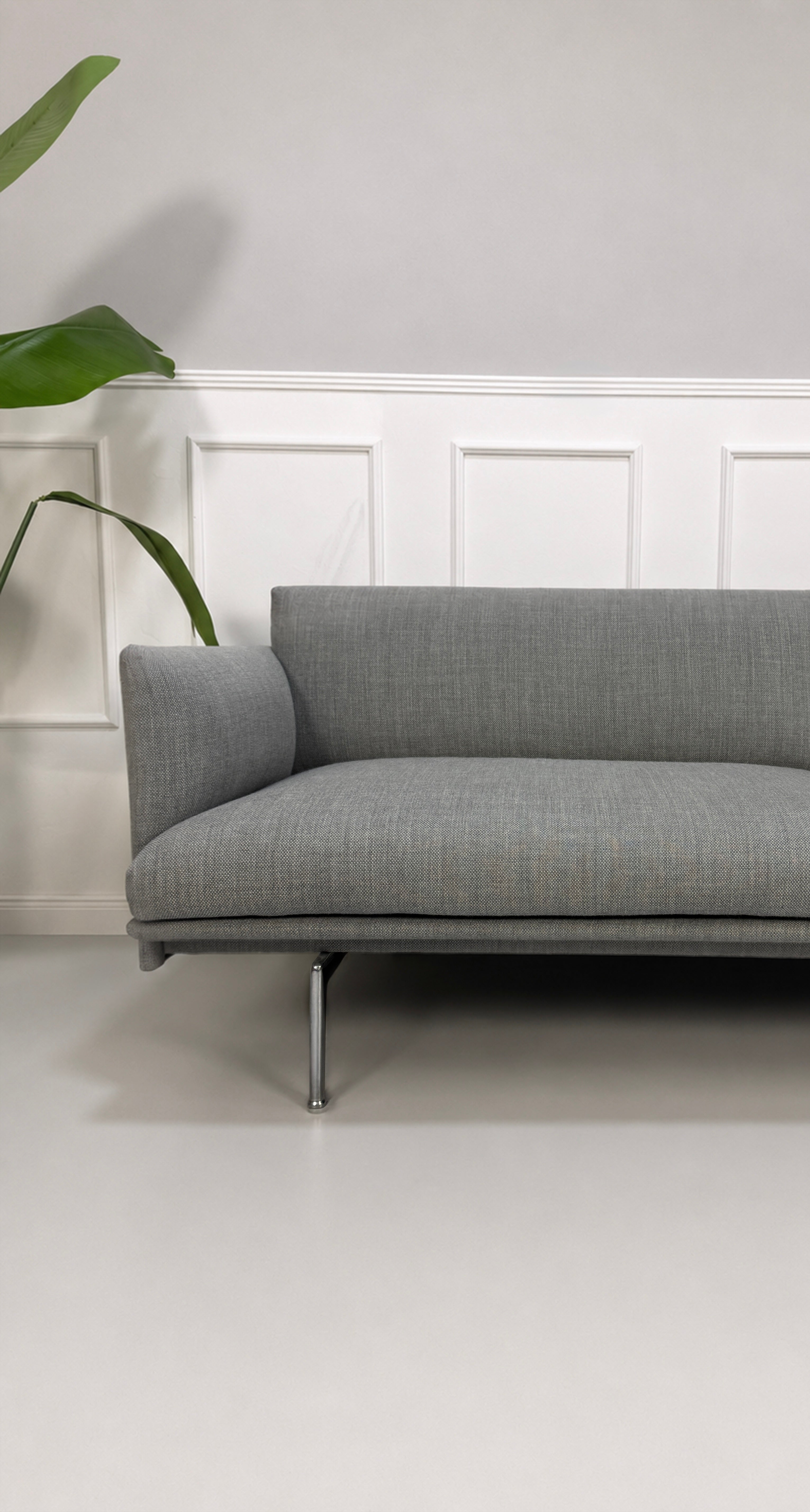 Gebrauchtes graues Muuto Outline Designer Stoff Sofa vor einer Wand, stilvoll und modern eingerichtet.