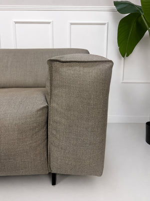 Gebrauchtes graues Rolf Benz Grata Designer Stoff Sofa mit Hocker vor einer Wand, stilvoll und modern eingerichtet.