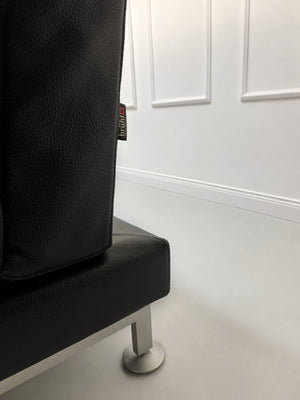 Gebrauchtes schwarzes Brühl Moule Designer Leder Sofa vor einer Wand, stilvoll und modern eingerichtet.