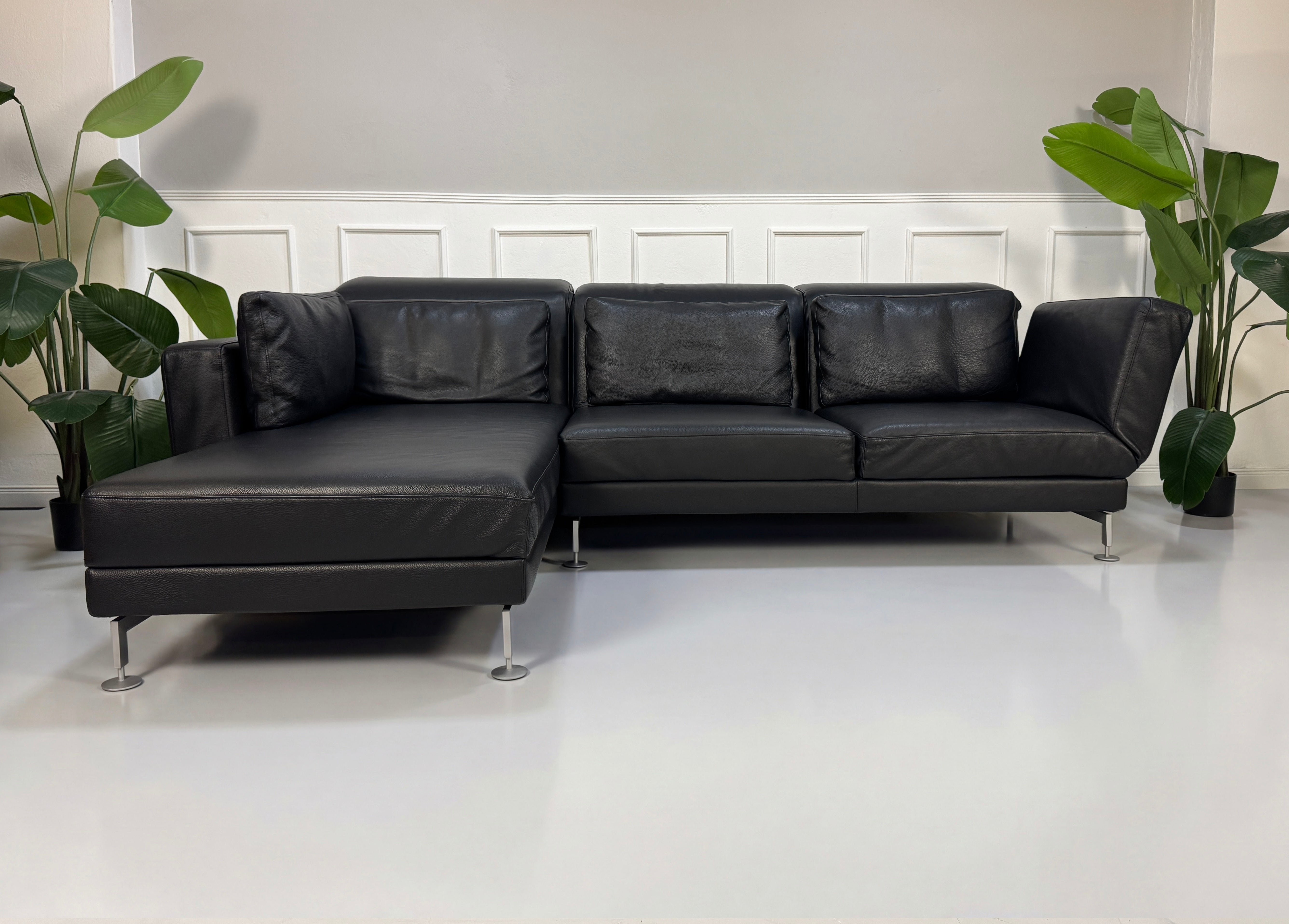 Gebrauchtes schwarzes Brühl Moule Designer Leder Sofa vor einer Wand, stilvoll und modern eingerichtet.
