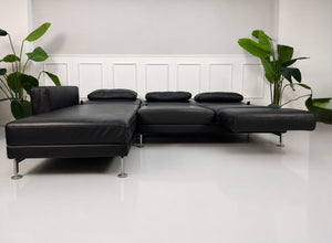 Gebrauchtes schwarzes Brühl Moule Designer Leder Sofa vor einer Wand, stilvoll und modern eingerichtet.