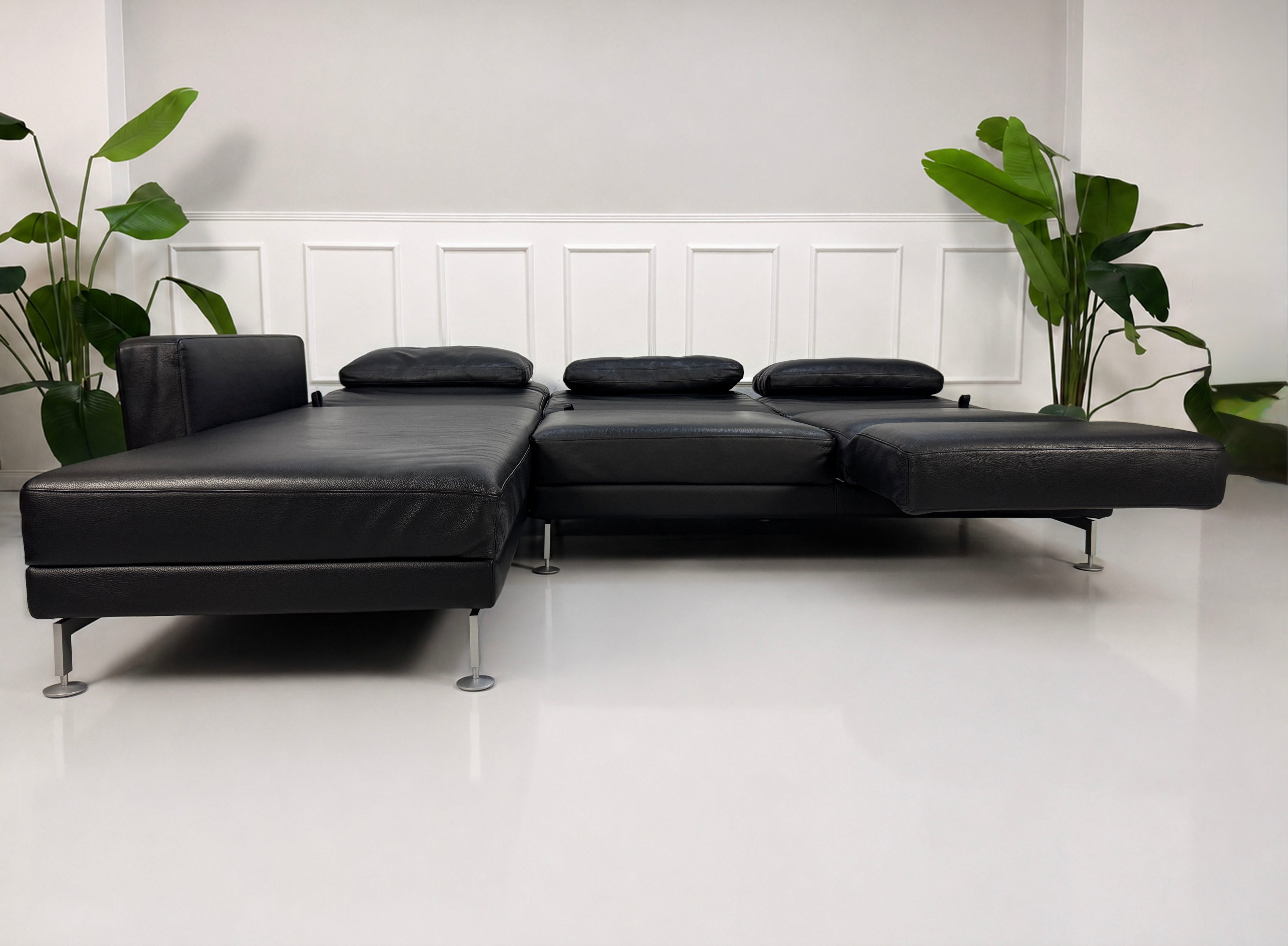 Gebrauchtes schwarzes Brühl Moule Designer Leder Sofa vor einer Wand, stilvoll und modern eingerichtet.