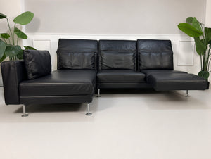 Gebrauchtes schwarzes Brühl Moule Designer Leder Sofa vor einer Wand, stilvoll und modern eingerichtet.
