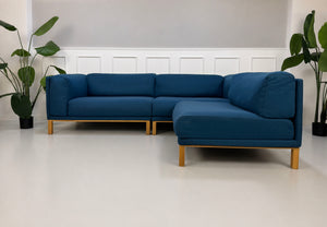 Gebrauchtes blaues Bolia Cosy Designer Stoff Sofa vor einer Wand, stilvoll und modern eingerichtet.