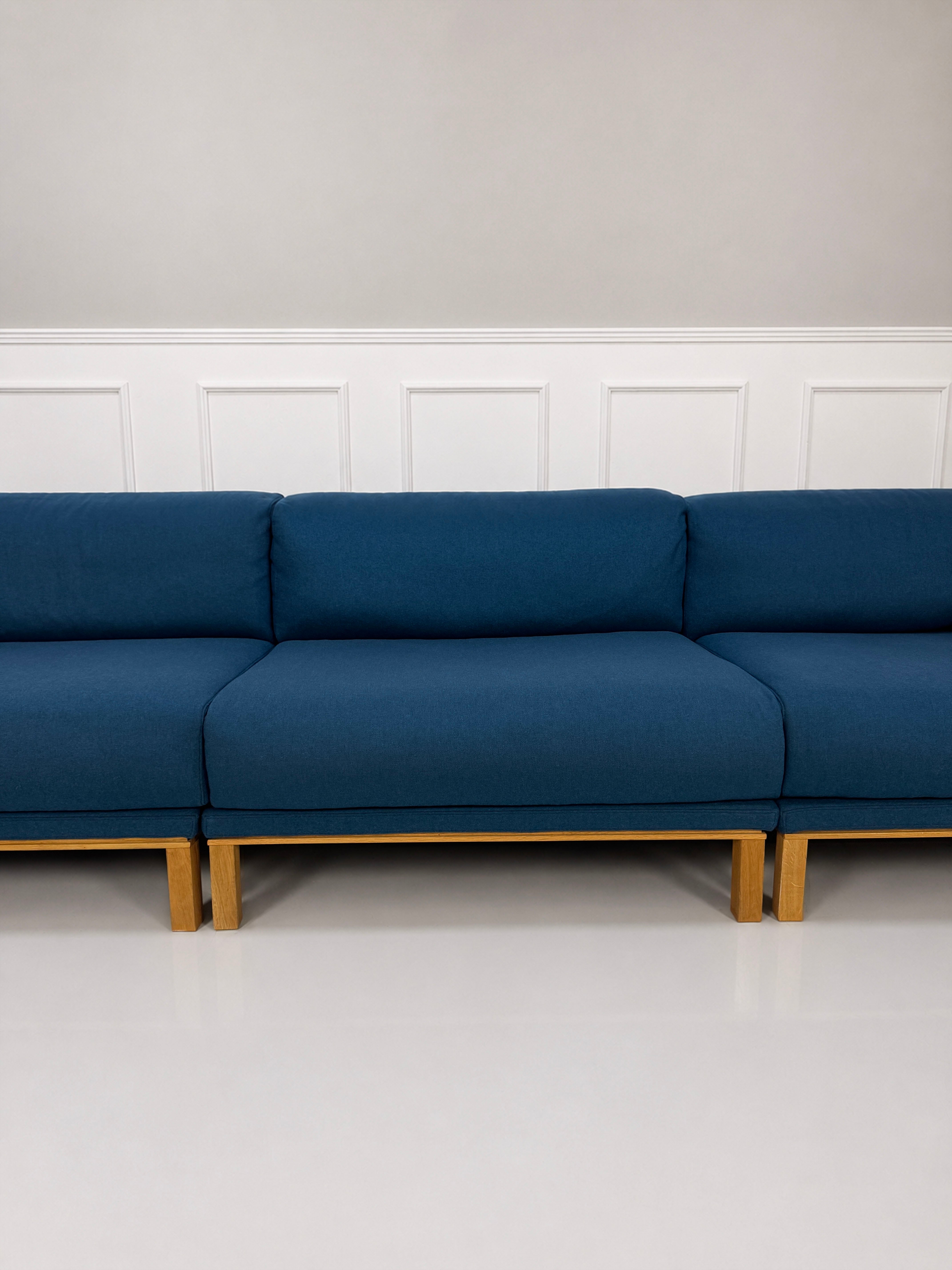 Gebrauchtes blaues Bolia Cosy Designer Stoff Sofa vor einer Wand, stilvoll und modern eingerichtet.