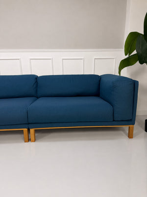 Gebrauchtes blaues Bolia Cosy Designer Stoff Sofa vor einer Wand, stilvoll und modern eingerichtet.