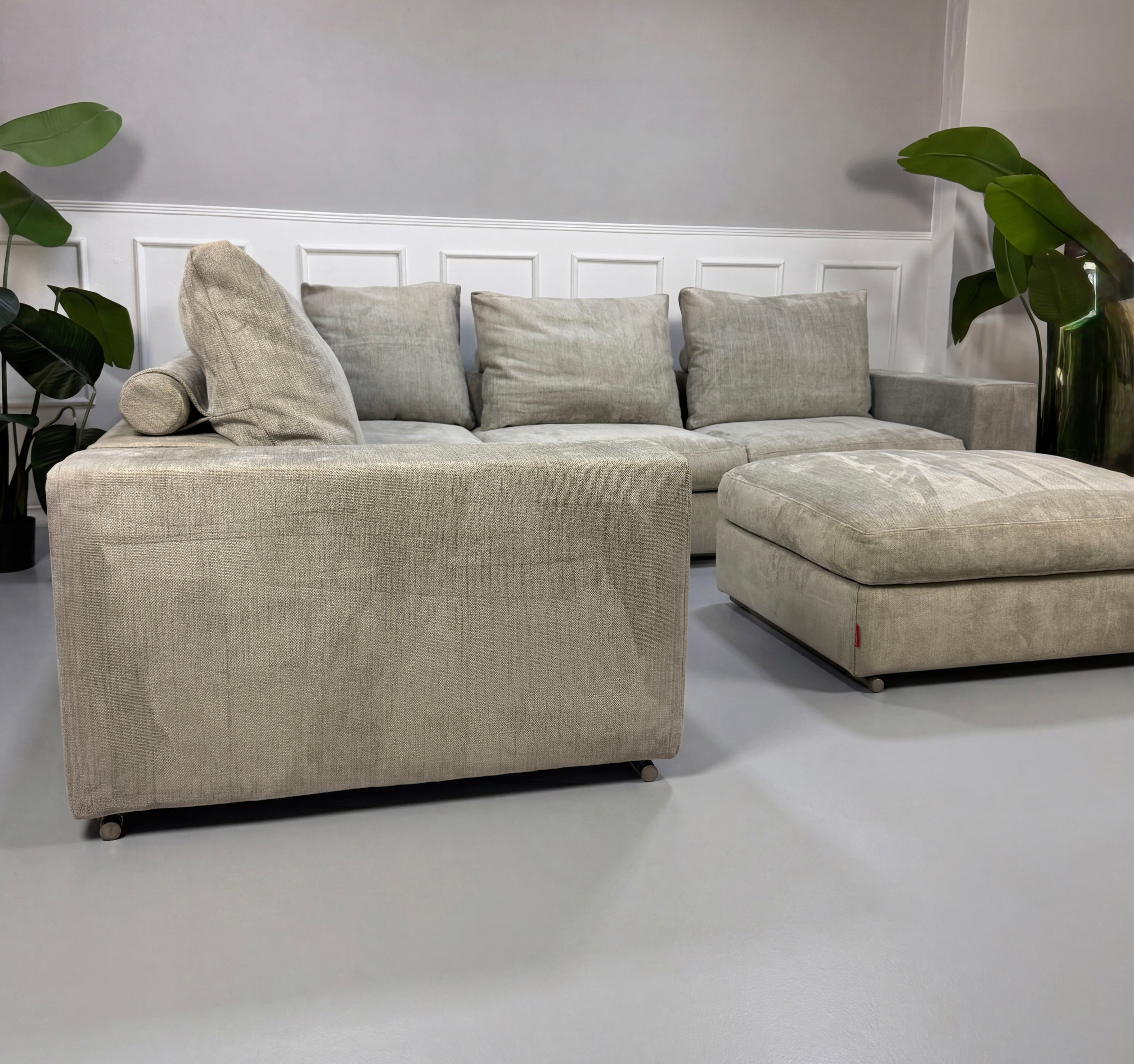 Gebrauchtes graues Flexform Groundpiece Designer Stoff Sofa vor einer Wand, stilvoll und modern eingerichtet.