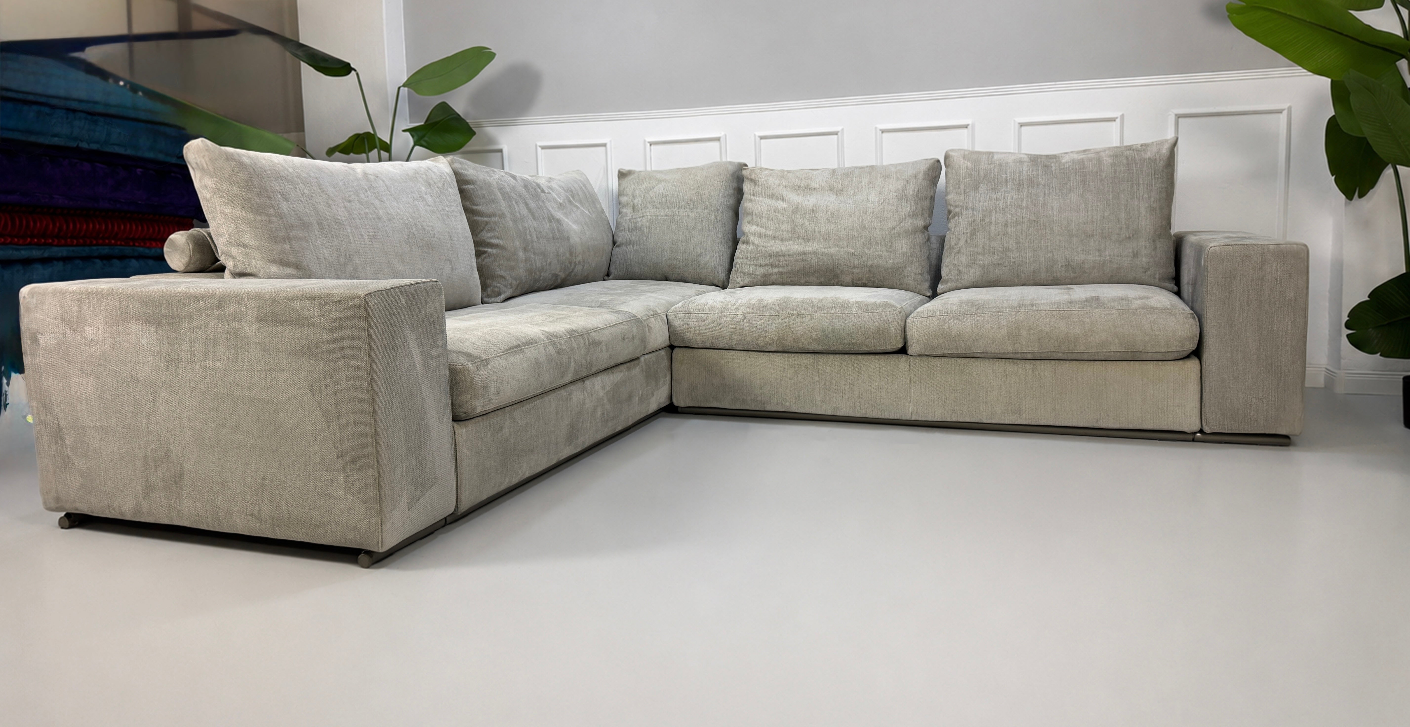 Gebrauchtes graues Flexform Groundpiece Designer Stoff Sofa vor einer Wand, stilvoll und modern eingerichtet.