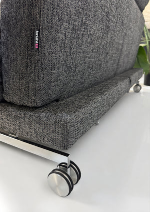 Gebrauchtes graues Brühl Moule Designer Stoff Sofa vor einer Wand, stilvoll und modern eingerichtet.