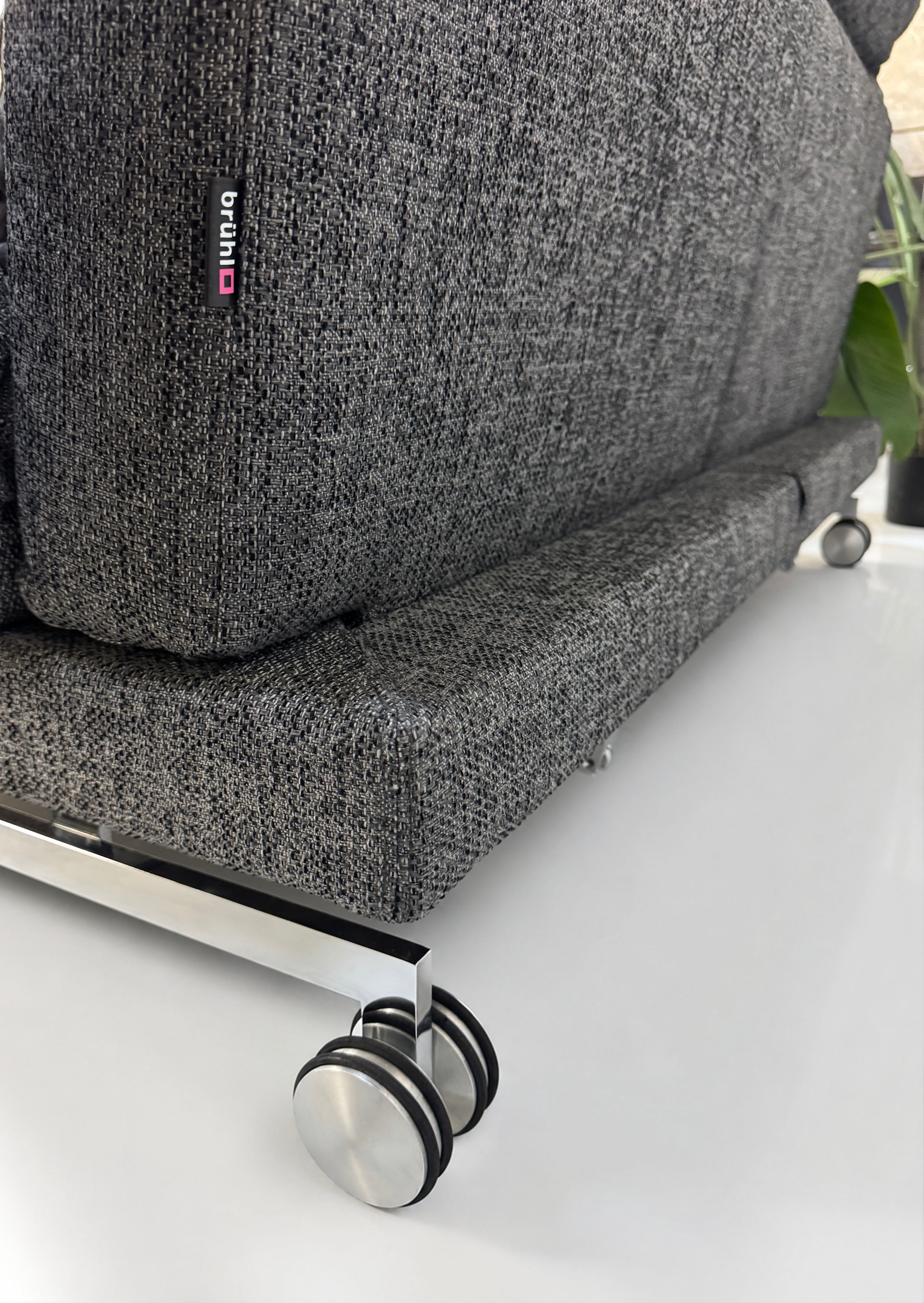 Gebrauchtes graues Brühl Moule Designer Stoff Sofa vor einer Wand, stilvoll und modern eingerichtet.