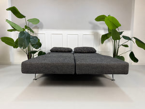 Gebrauchtes graues Brühl Moule Designer Stoff Sofa vor einer Wand, stilvoll und modern eingerichtet.