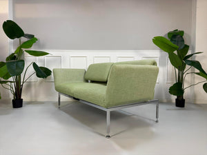 Fabrikverkauf grünes Brühl Roro Designer Stoff Sofa vor einer Wand, stilvoll und modern eingerichtet.