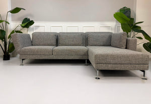 Gebrauchtes graues Brühl Moule Designer Stoff Sofa vor einer Wand, stilvoll und modern eingerichtet.