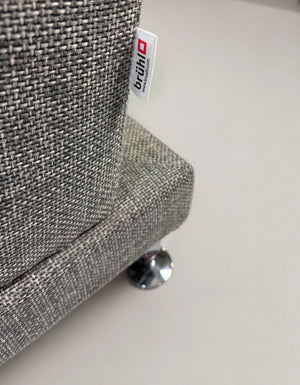 Gebrauchtes graues Brühl Moule Designer Stoff Sofa vor einer Wand, stilvoll und modern eingerichtet.