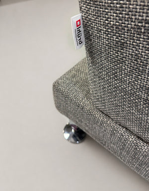 Gebrauchtes graues Brühl Designer Stoff Sofa vor einer Wand, stilvoll und modern eingerichtet.