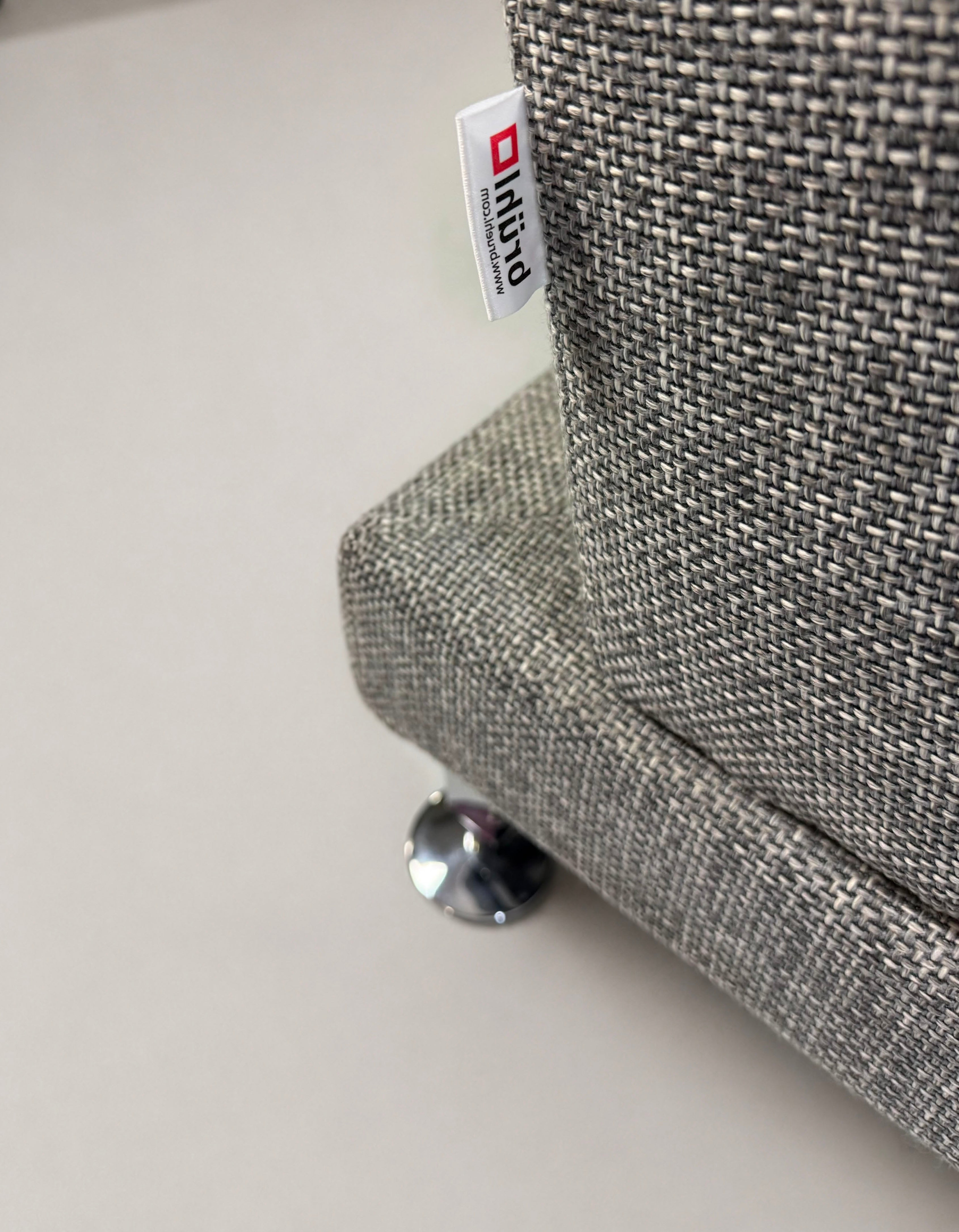 Gebrauchtes graues Brühl Designer Stoff Sofa vor einer Wand, stilvoll und modern eingerichtet.