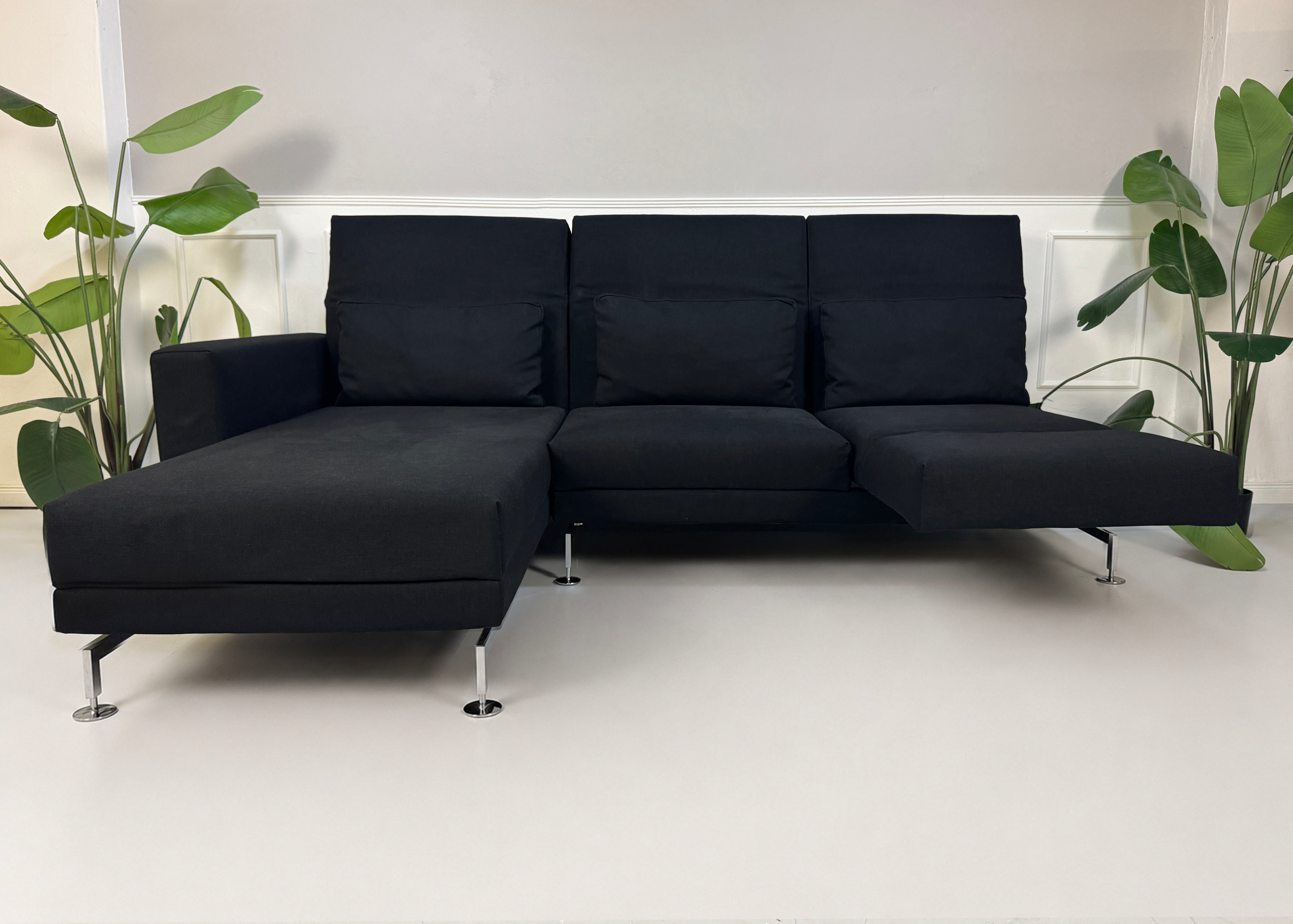 Gebrauchtes schwarzes Brühl Moule Designer Stoff Sofa vor einer Wand, stilvoll und modern eingerichtet.