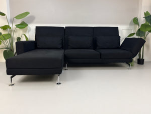 Gebrauchtes schwarzes Brühl Moule Designer Stoff Sofa vor einer Wand, stilvoll und modern eingerichtet.
