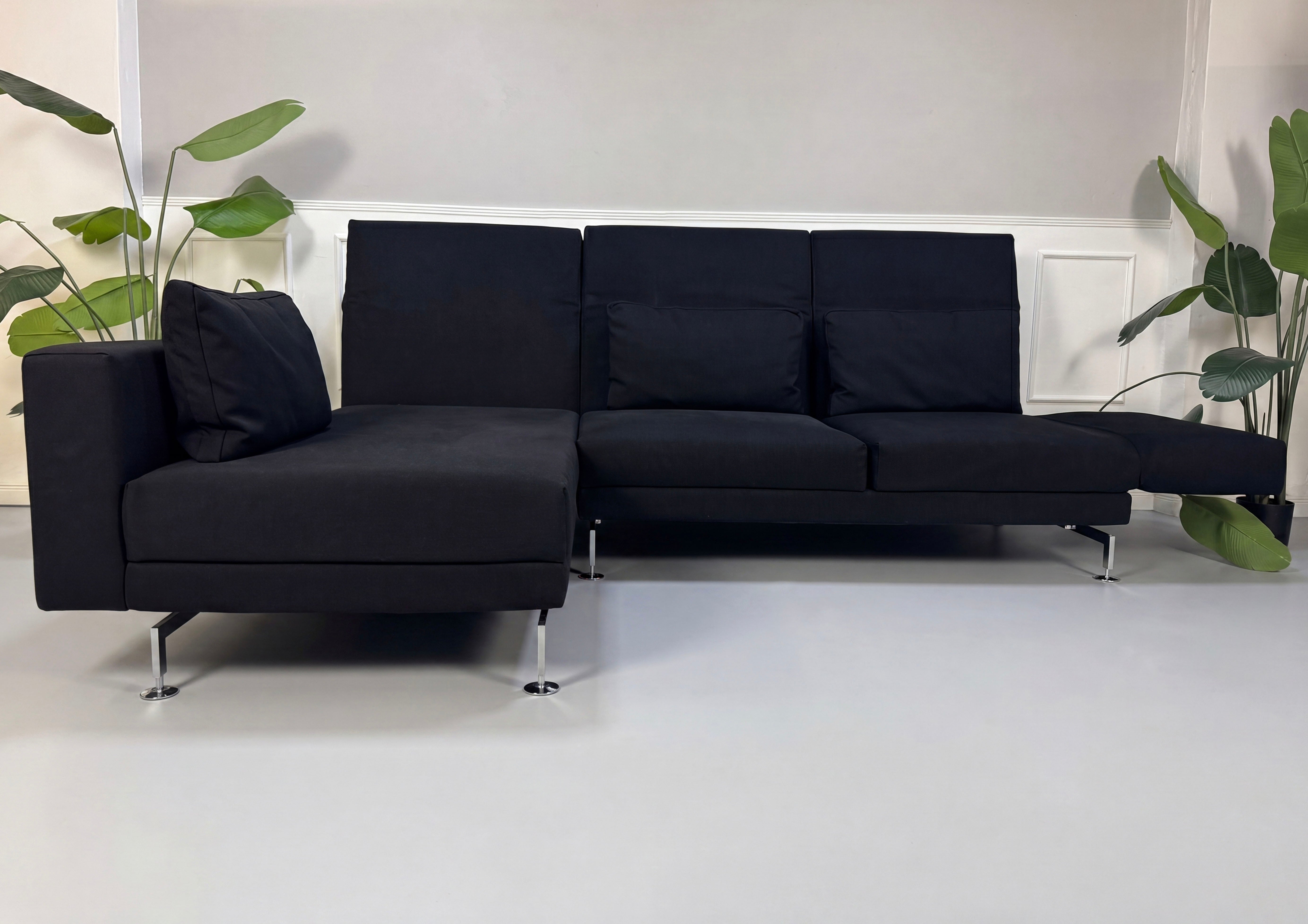 Gebrauchtes schwarzes Brühl Moule Designer Stoff Sofa vor einer Wand, stilvoll und modern eingerichtet.