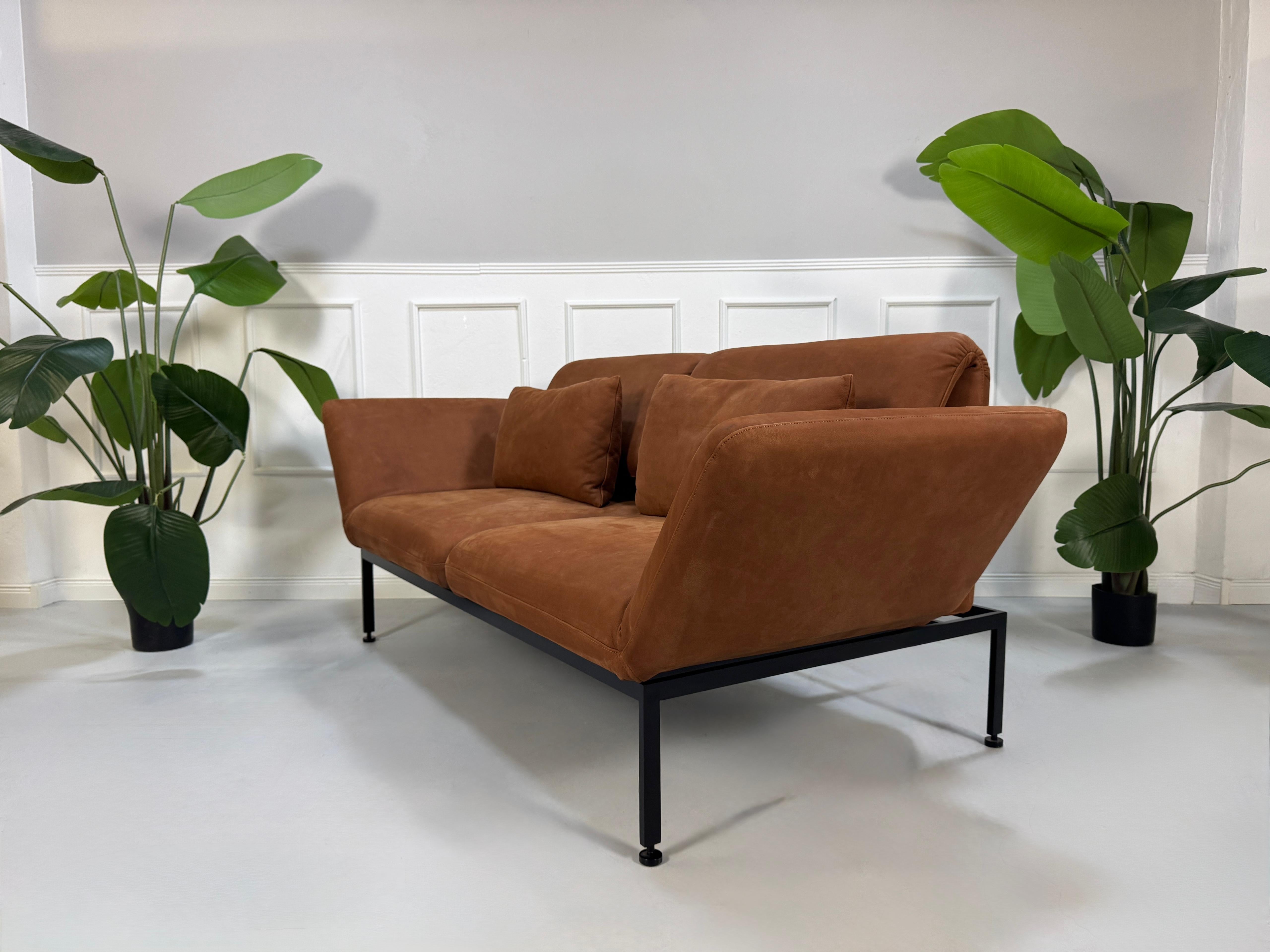 Gebrauchtes braunes Brühl Roro Designer Leder Taron Sofa vor einer Wand, stilvoll und modern eingerichtet.