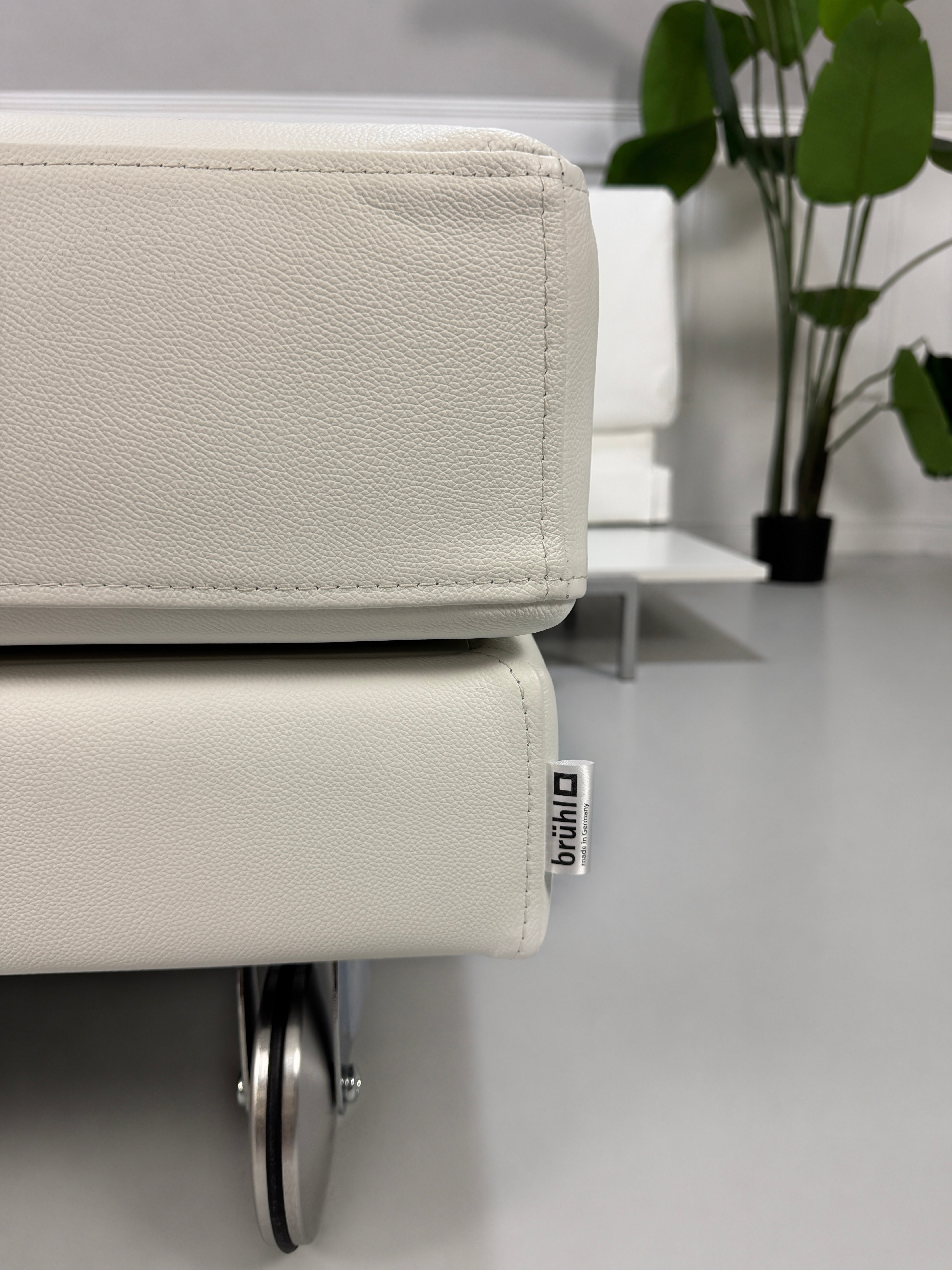 Ausstellungsstück weißes Brühl FourTwo  Designer Leder Sofa vor einer Wand, stilvoll und modern eingerichtet.