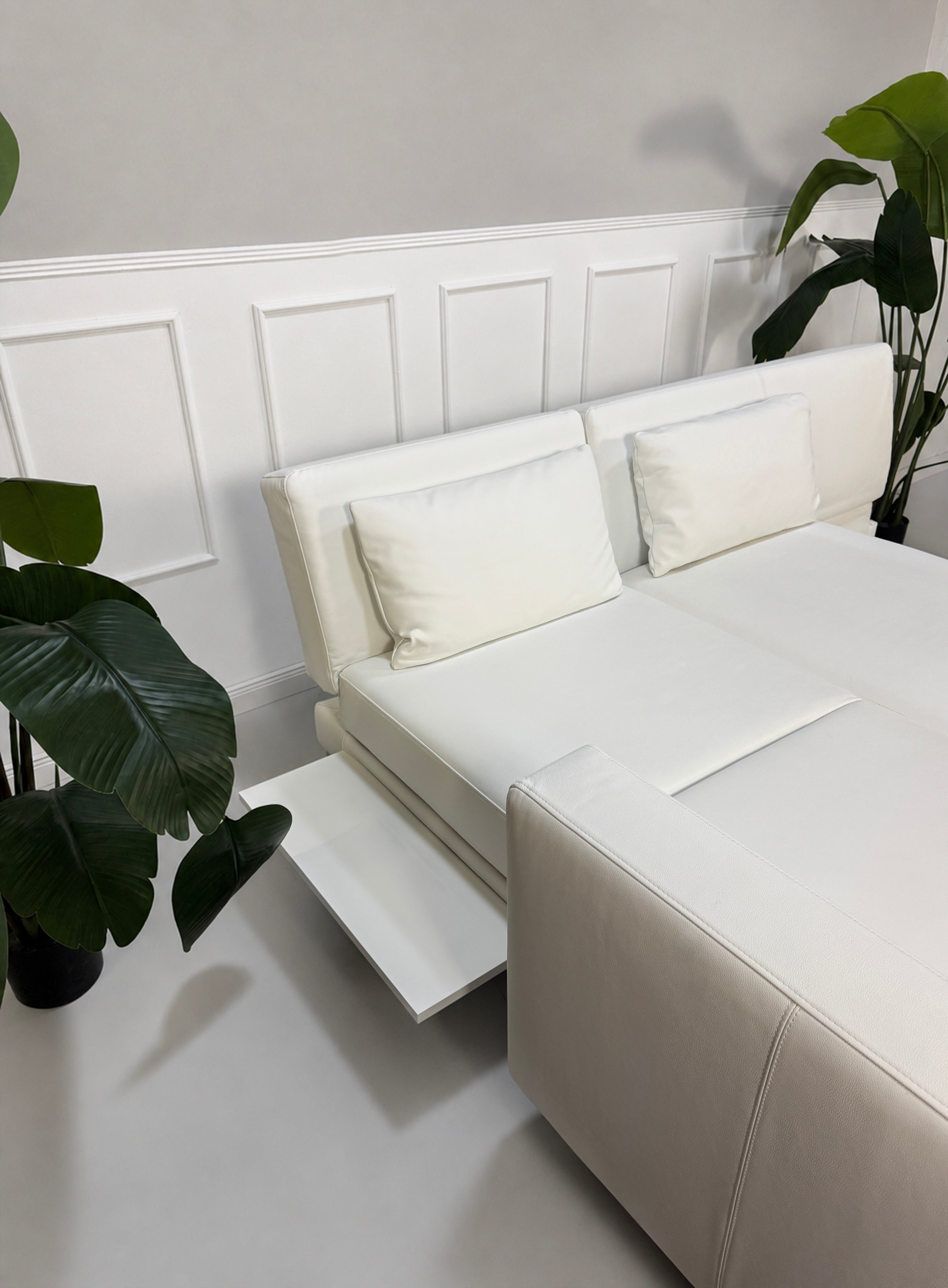 Ausstellungsstück weißes Brühl FourTwo  Designer Leder Sofa vor einer Wand, stilvoll und modern eingerichtet.