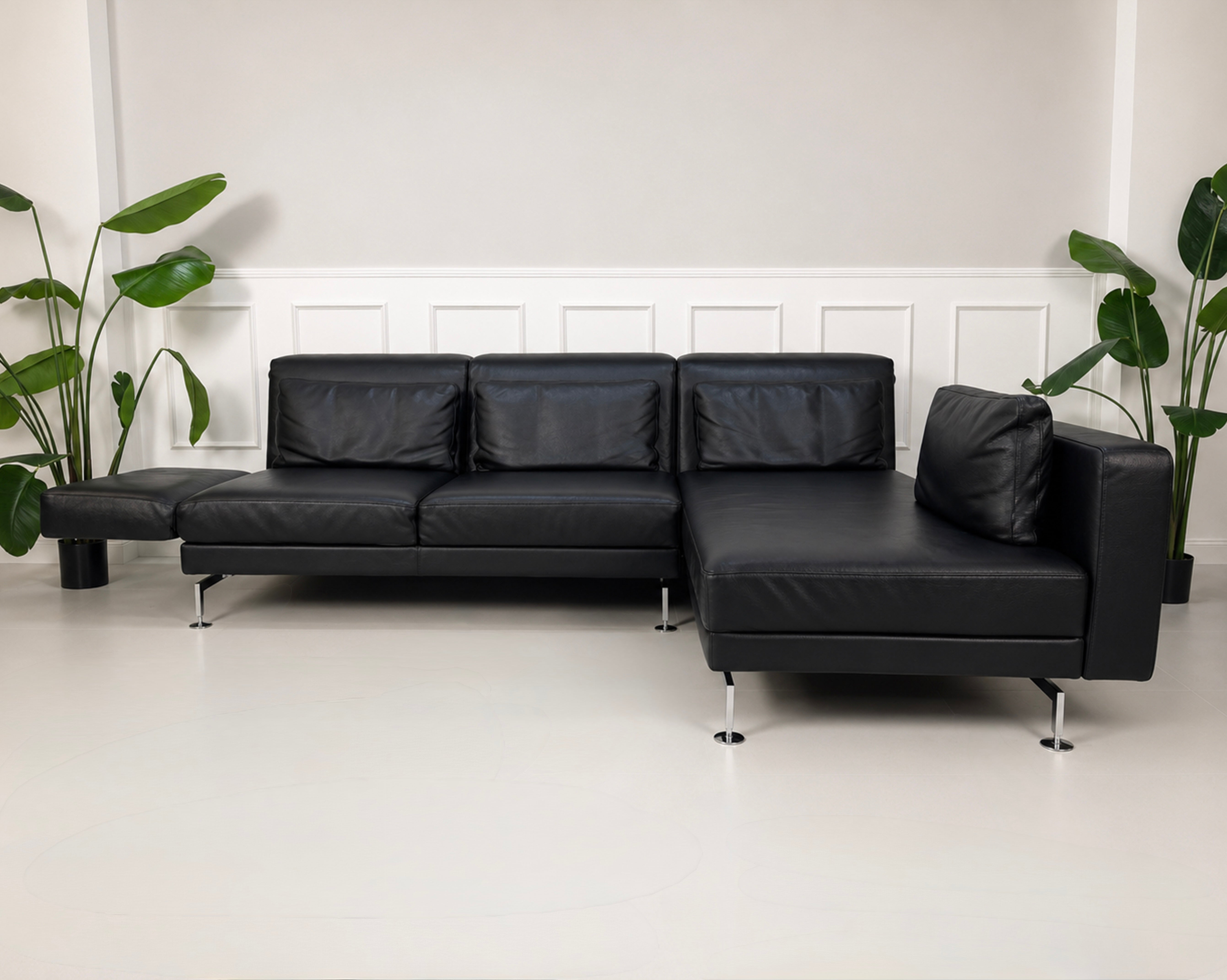 Gebrauchtes schwarzes Brühl Moule Designer Leder Sofa vor einer Wand, stilvoll und modern eingerichtet.